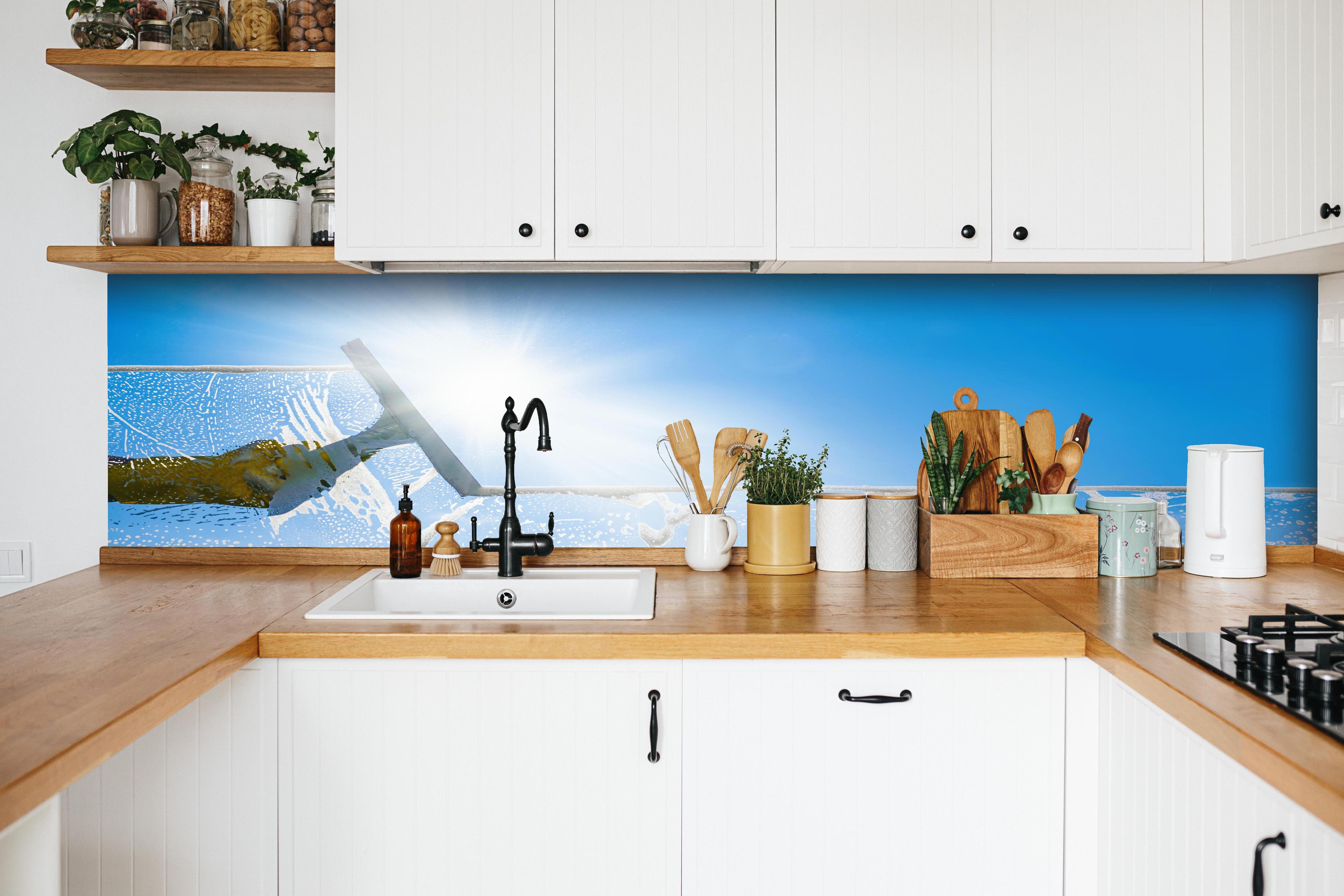 Küche - Fensterputzer mit Abzieher und strahlendem Himmel hinter weißen Hochglanz-Küchenregalen und schwarzem Wasserhahn