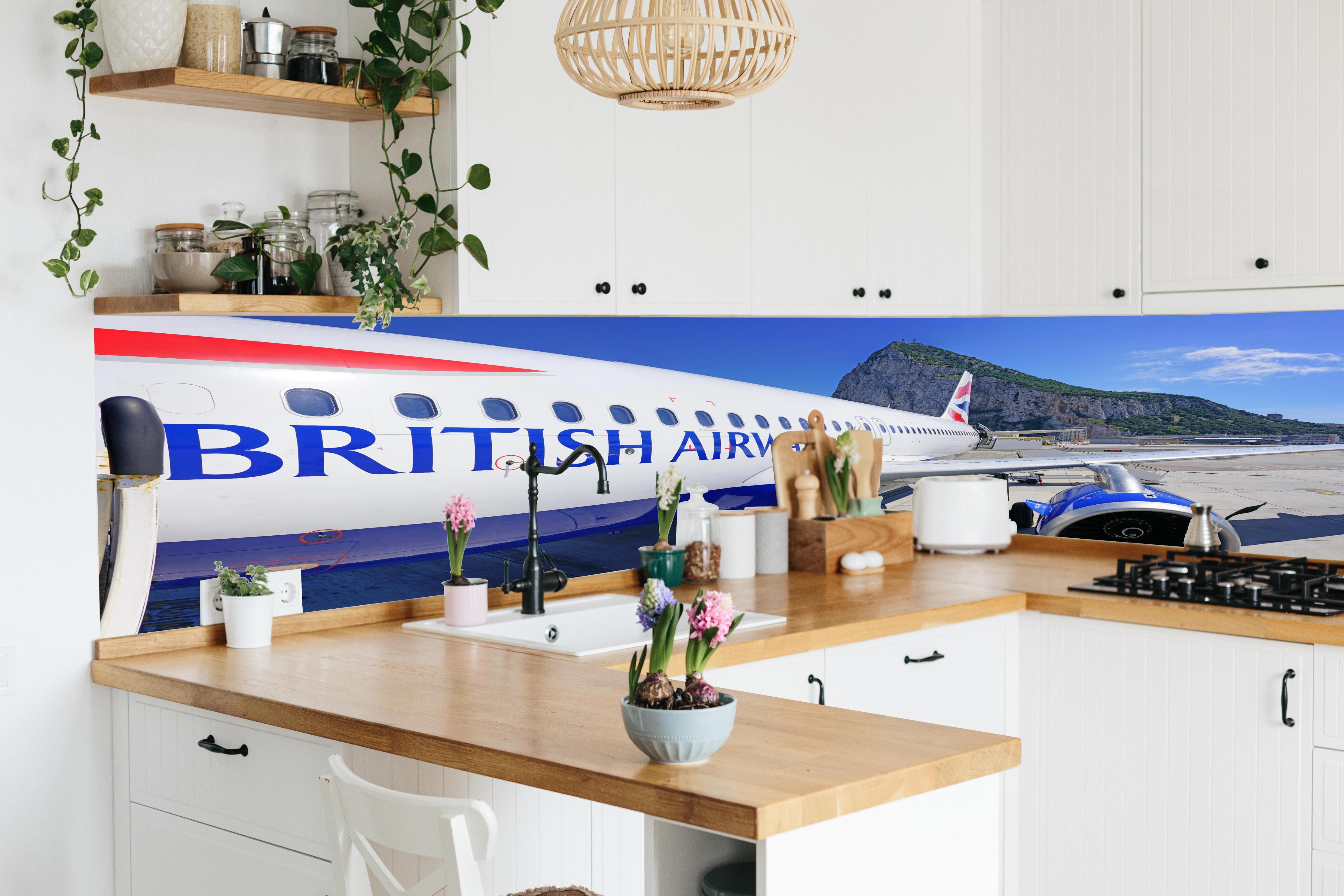 Küche - Flugzeug von British Airways hinter weißen Hochglanz-Küchenregalen und schwarzem Wasserhahn