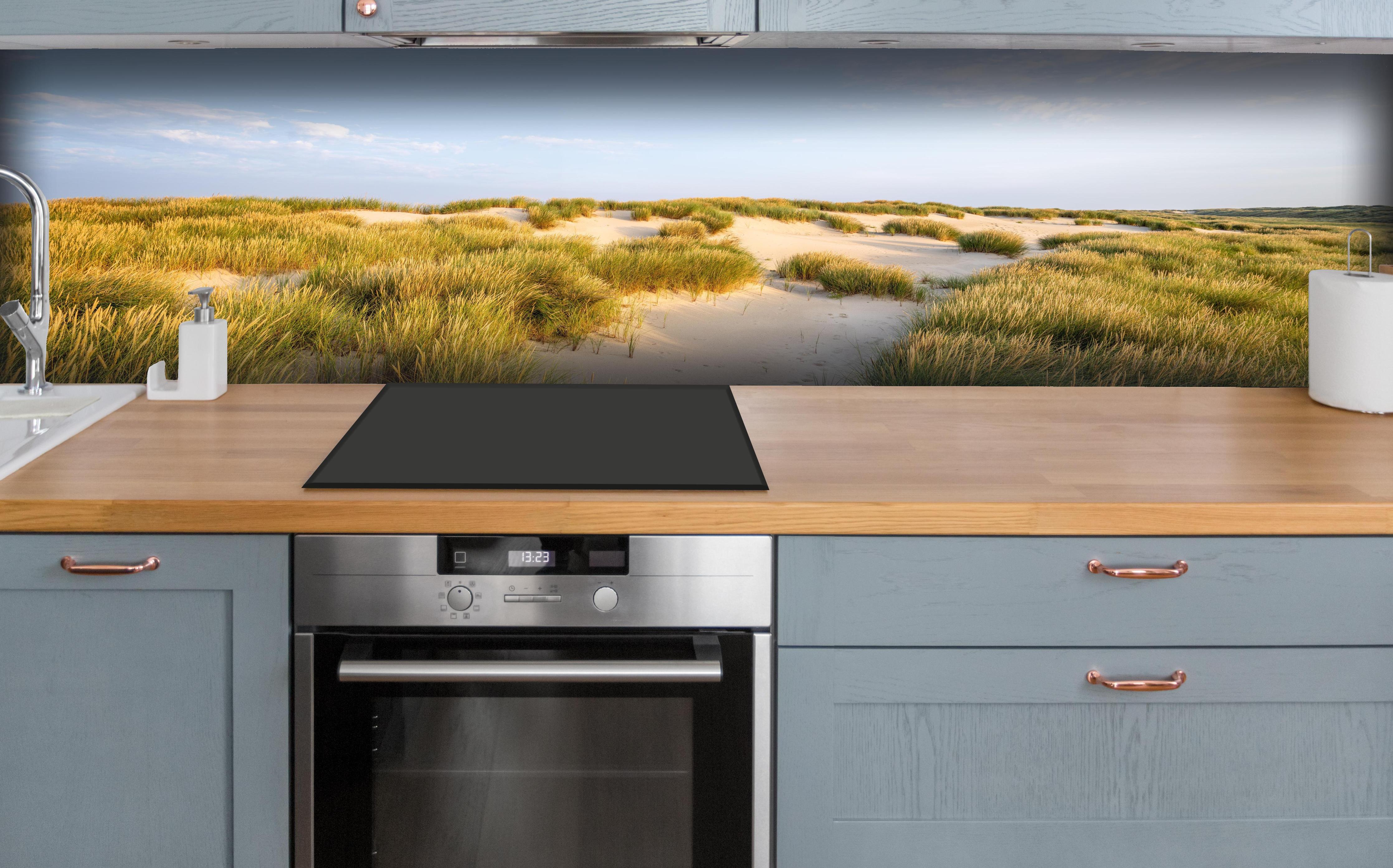 Küche - Friedliche Dünenlandschaft mit leuchtendem Gras im warmen Sonnenlicht hinter weißen Hochglanz-Küchenregalen und schwarzem Wasserhahn