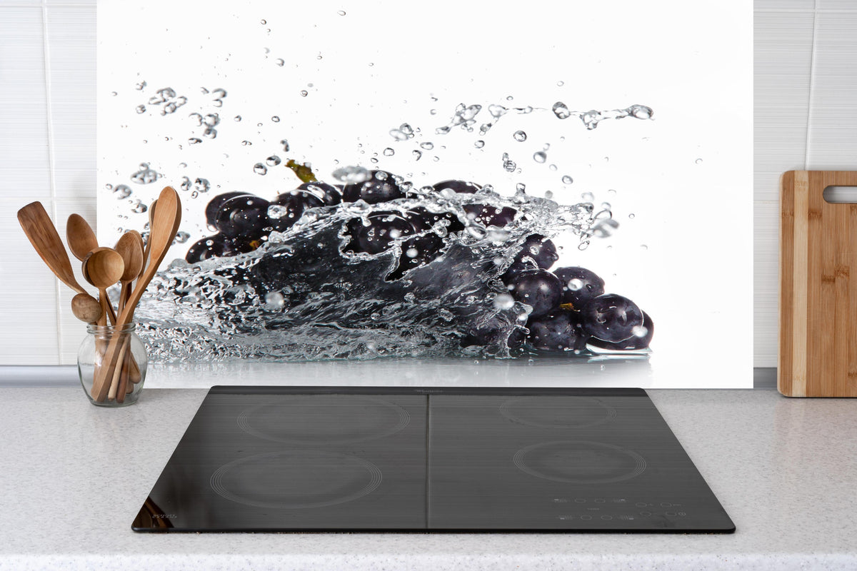 Küche - Frische Trauben im Wasser Splash hinter weißen Hochglanz-Küchenregalen und schwarzem Wasserhahn