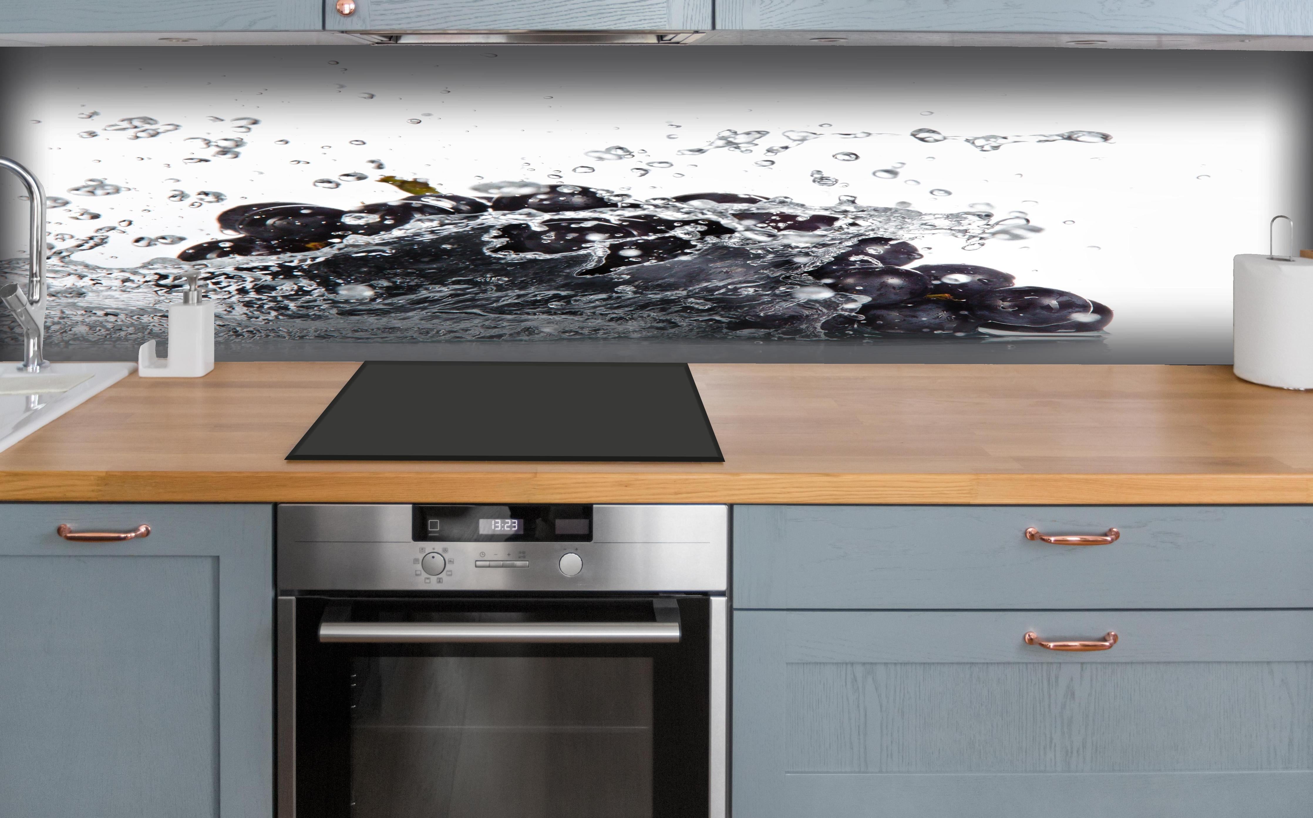 Küche - Frische Trauben im Wasser Splash hinter weißen Hochglanz-Küchenregalen und schwarzem Wasserhahn