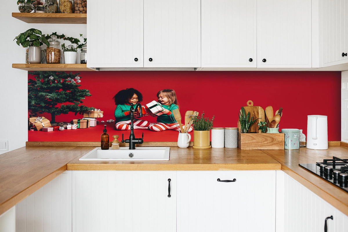 Küche - Fröhliche Kinder tauschen Weihnachtsgeschenke aus hinter weißen Hochglanz-Küchenregalen und schwarzem Wasserhahn