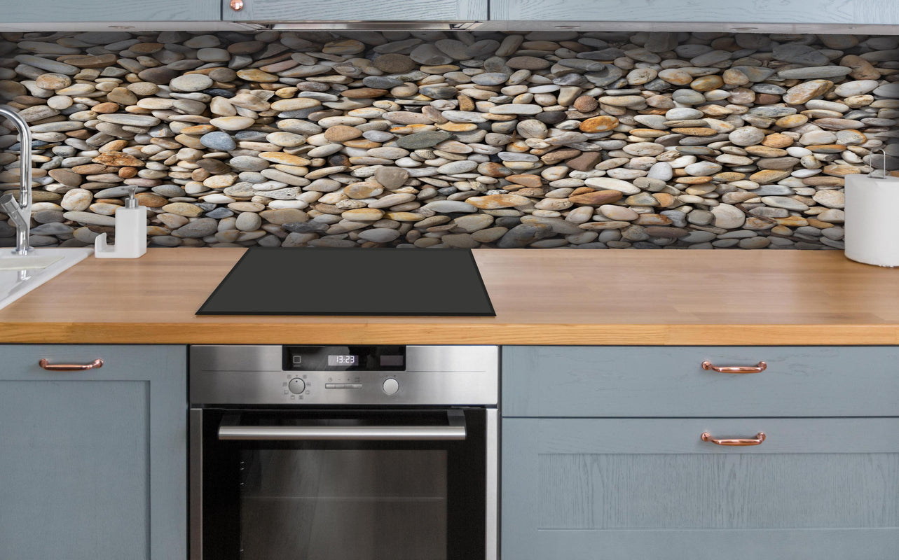 Küche - Grau-Beige Natürliche Kieselstein-Textur hinter weißen Hochglanz-Küchenregalen und schwarzem Wasserhahn