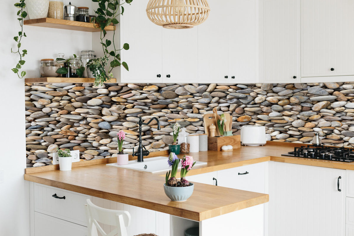 Küche - Grau-Beige Natürliche Kieselstein-Textur hinter weißen Hochglanz-Küchenregalen und schwarzem Wasserhahn