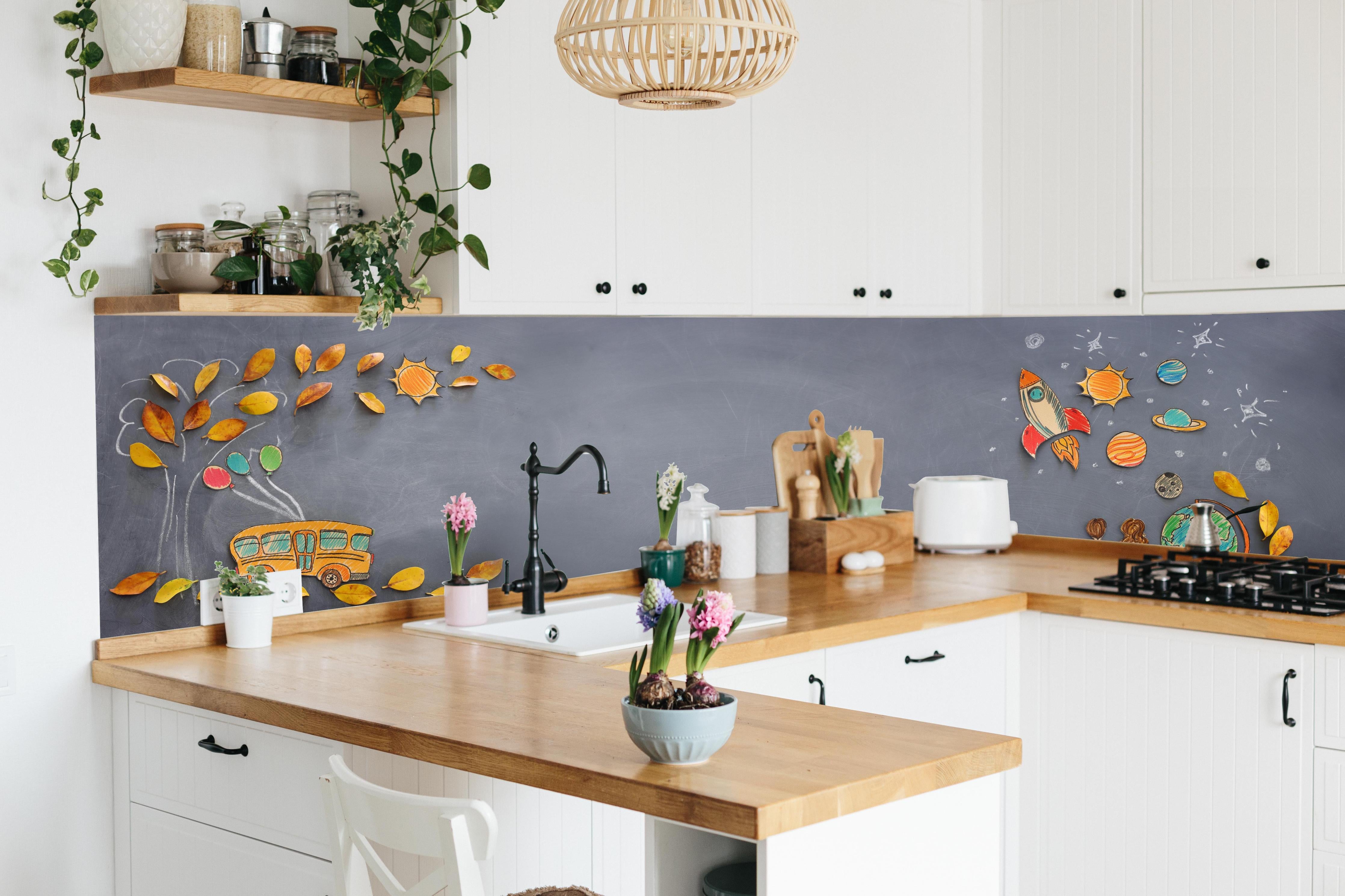 Küche - Herbstleaves und Schulbus auf Tafel hinter weißen Hochglanz-Küchenregalen und schwarzem Wasserhahn