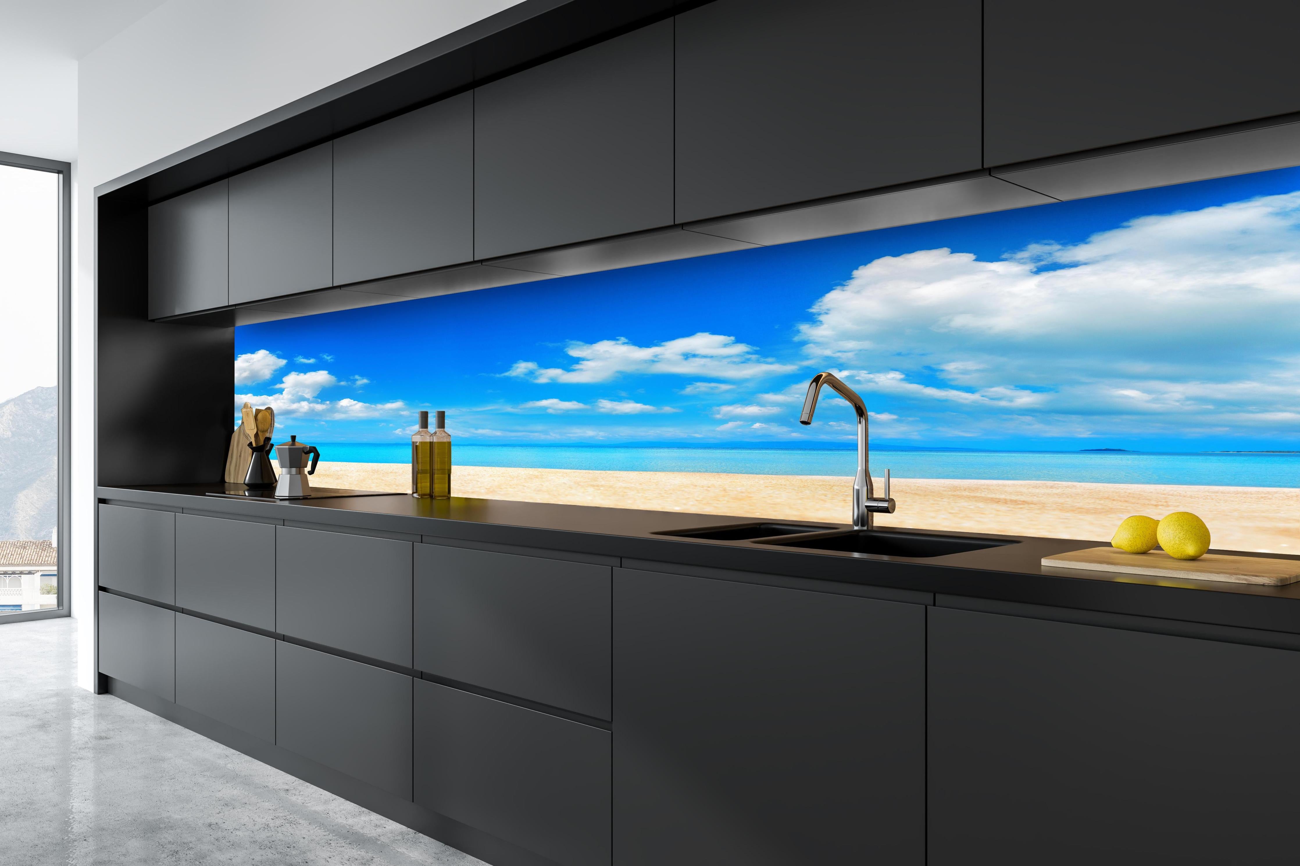 Küche - Idyllische Strandlandschaft mit klarem Wasser und blauem Himmel hinter weißen Hochglanz-Küchenregalen und schwarzem Wasserhahn
