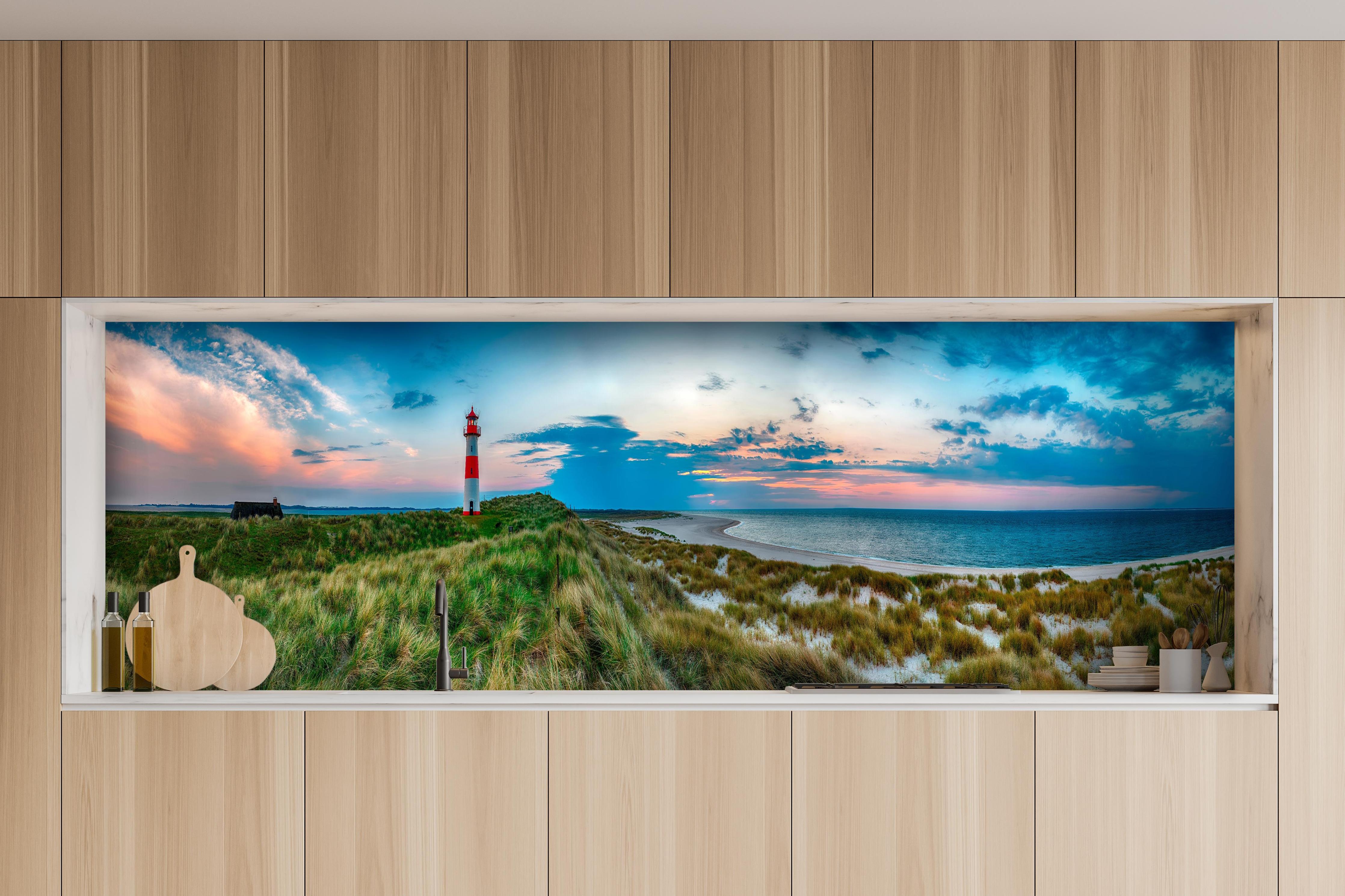 Küche - Idyllischer Leuchtturm mit traumhaften Ausblick auf den Sonnenuntergang am Meer hinter weißen Hochglanz-Küchenregalen und schwarzem Wasserhahn