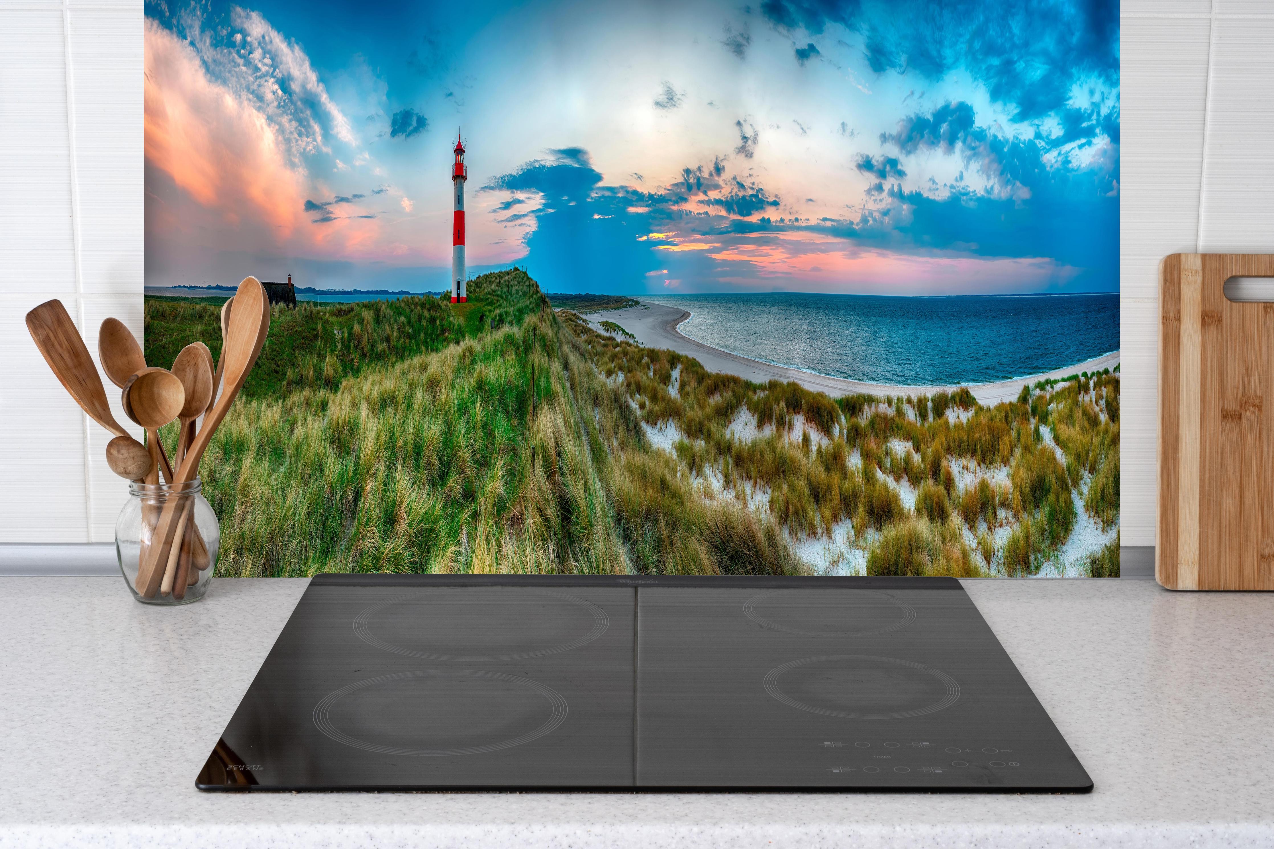 Küche - Idyllischer Leuchtturm mit traumhaften Ausblick auf den Sonnenuntergang am Meer hinter weißen Hochglanz-Küchenregalen und schwarzem Wasserhahn