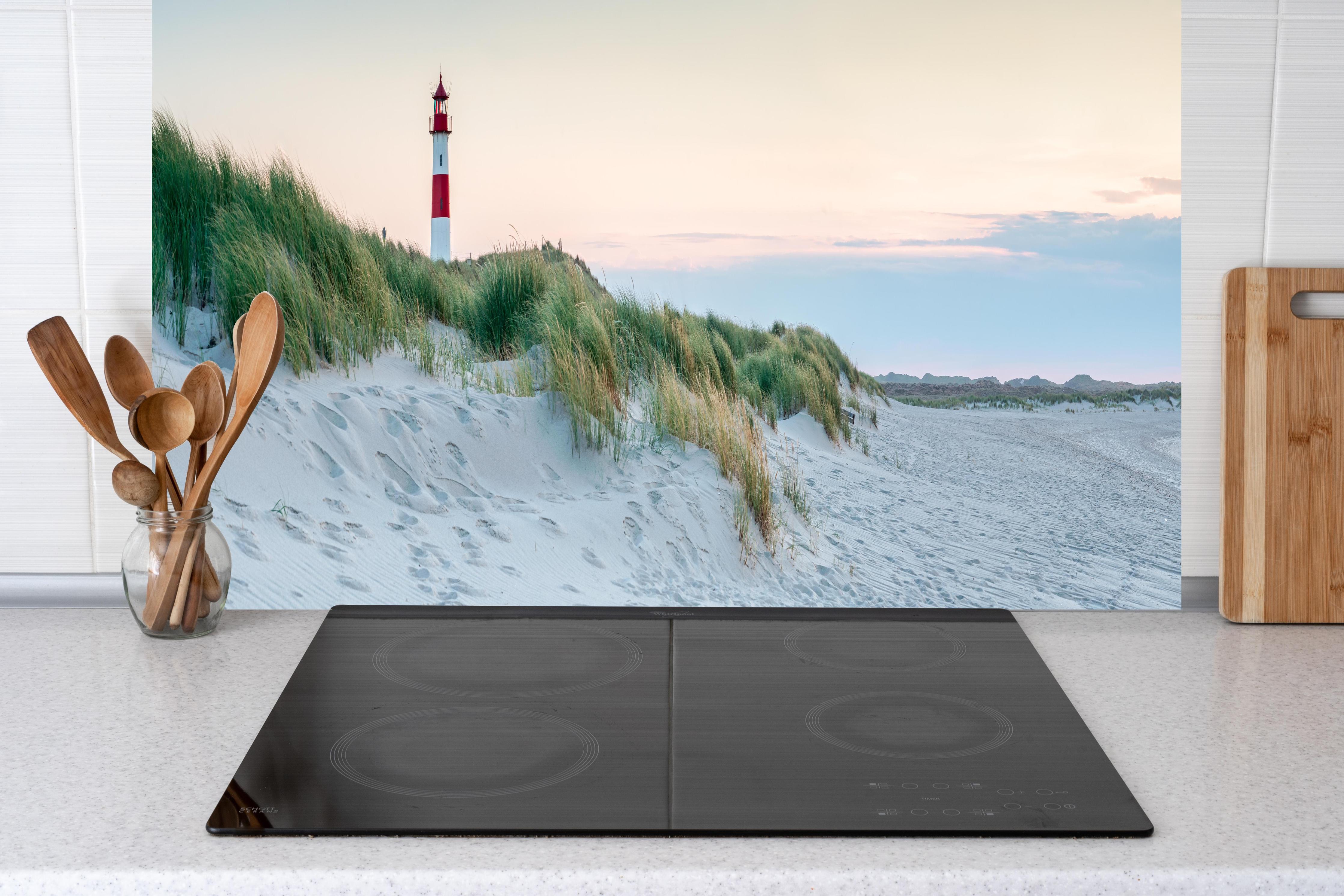 Küche - Idyllischer Leuchtturm zwischen Sanddünen und sanften Wellen hinter weißen Hochglanz-Küchenregalen und schwarzem Wasserhahn