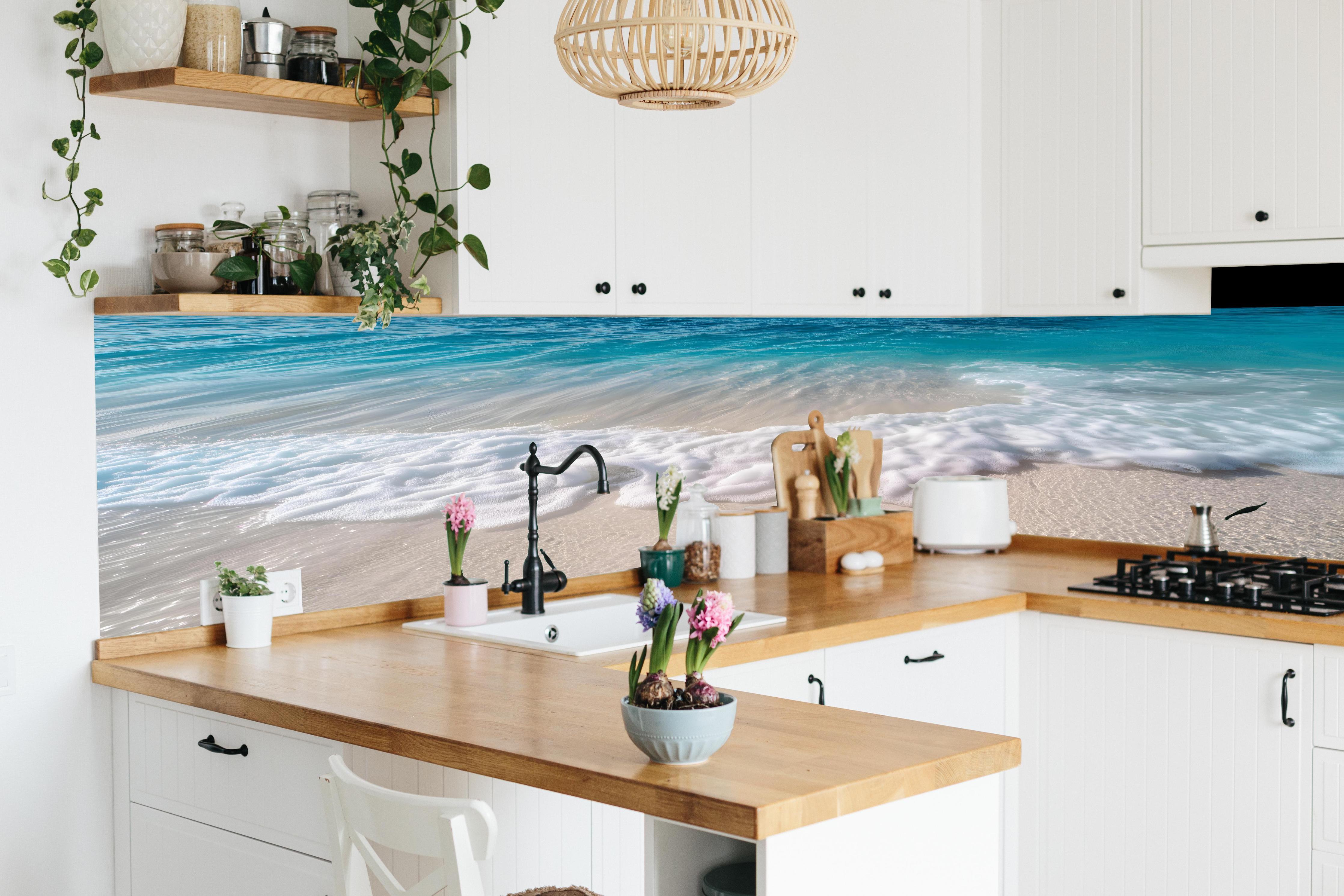 Küche - Idyllischer Strand mit sanften Wellen und weißem Schaum hinter weißen Hochglanz-Küchenregalen und schwarzem Wasserhahn
