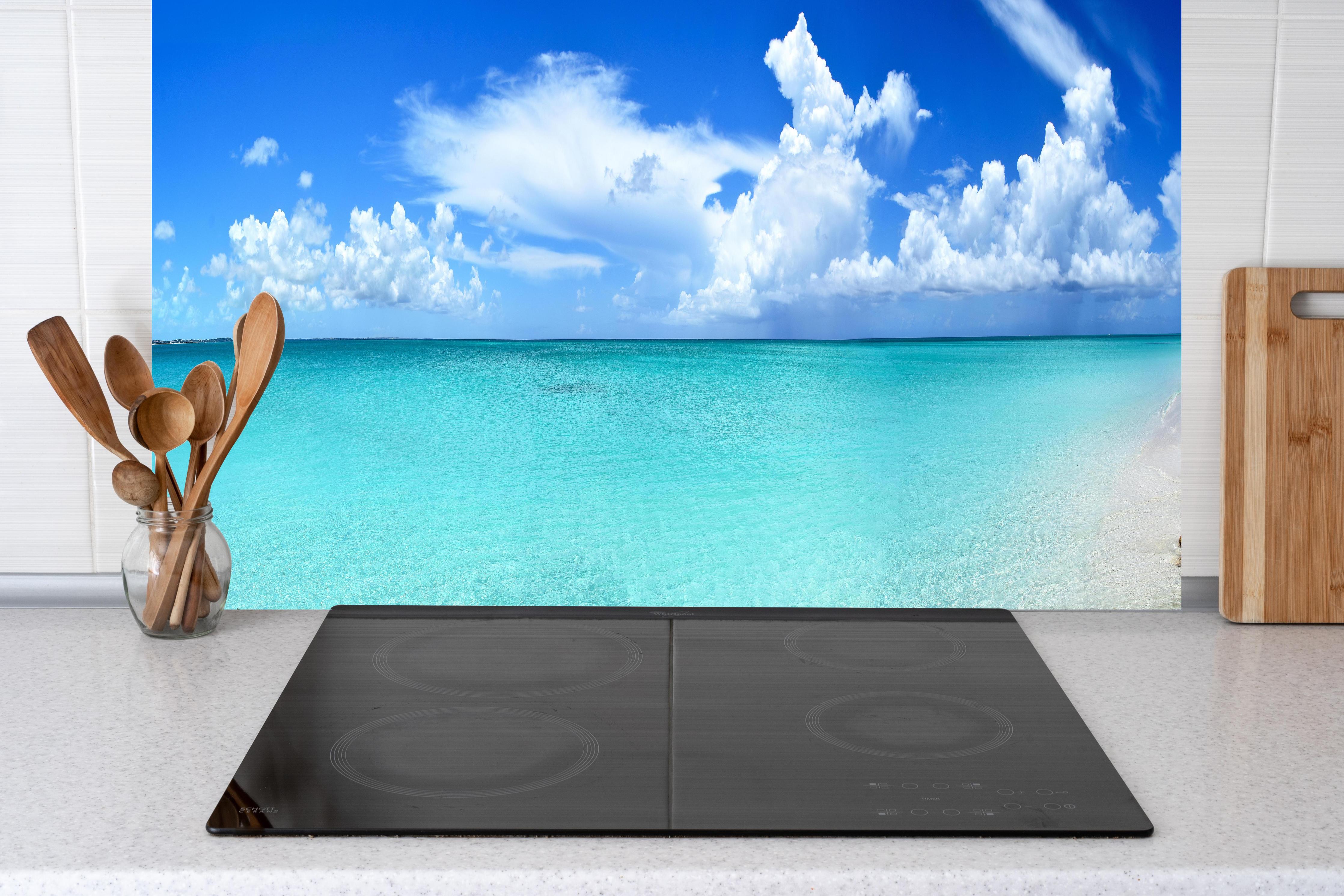 Küche - Idyllischer Strand unter einem strahlend blauen Himmel hinter weißen Hochglanz-Küchenregalen und schwarzem Wasserhahn