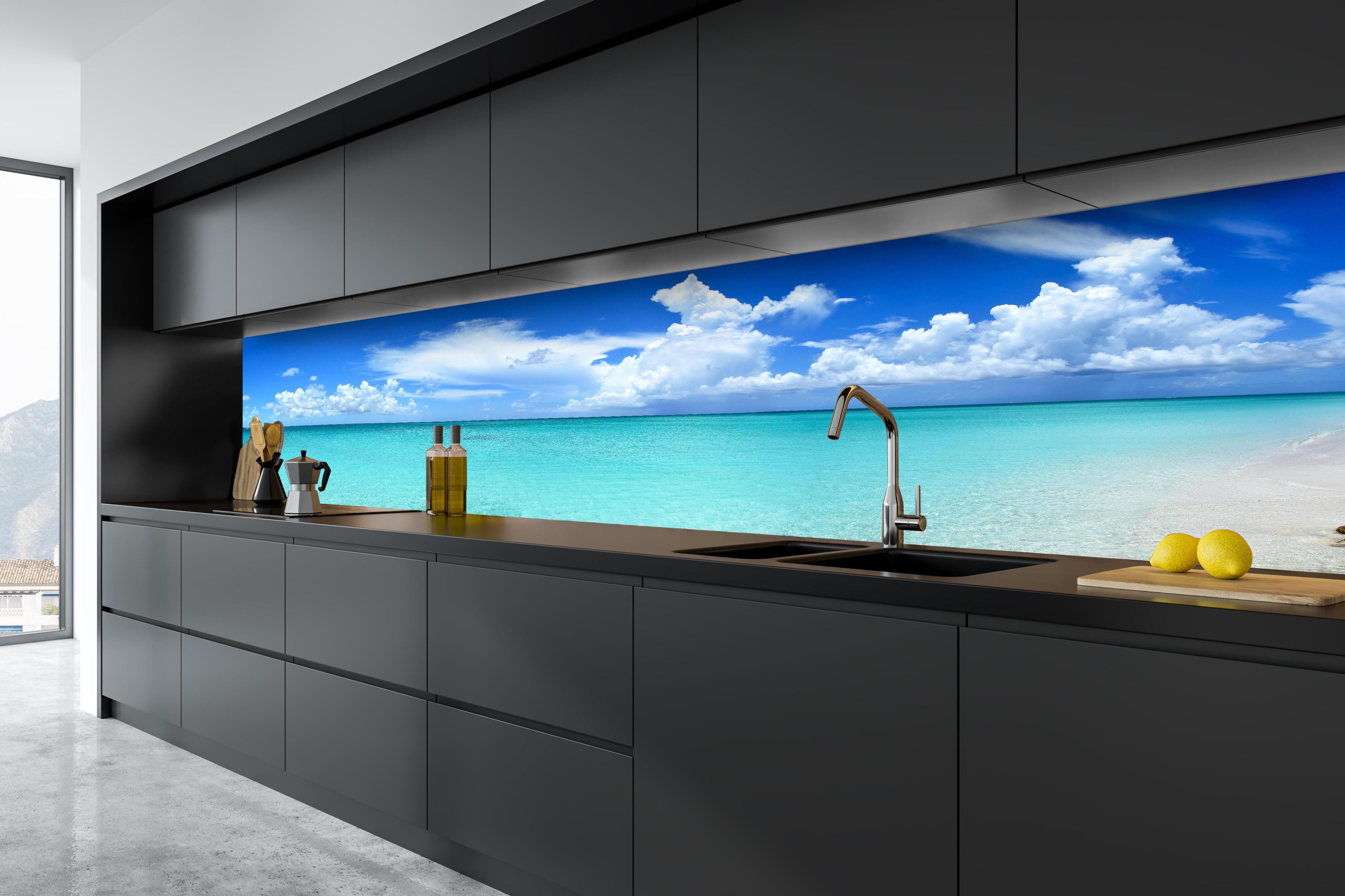 Küche - Idyllischer Strand unter einem strahlend blauen Himmel hinter weißen Hochglanz-Küchenregalen und schwarzem Wasserhahn