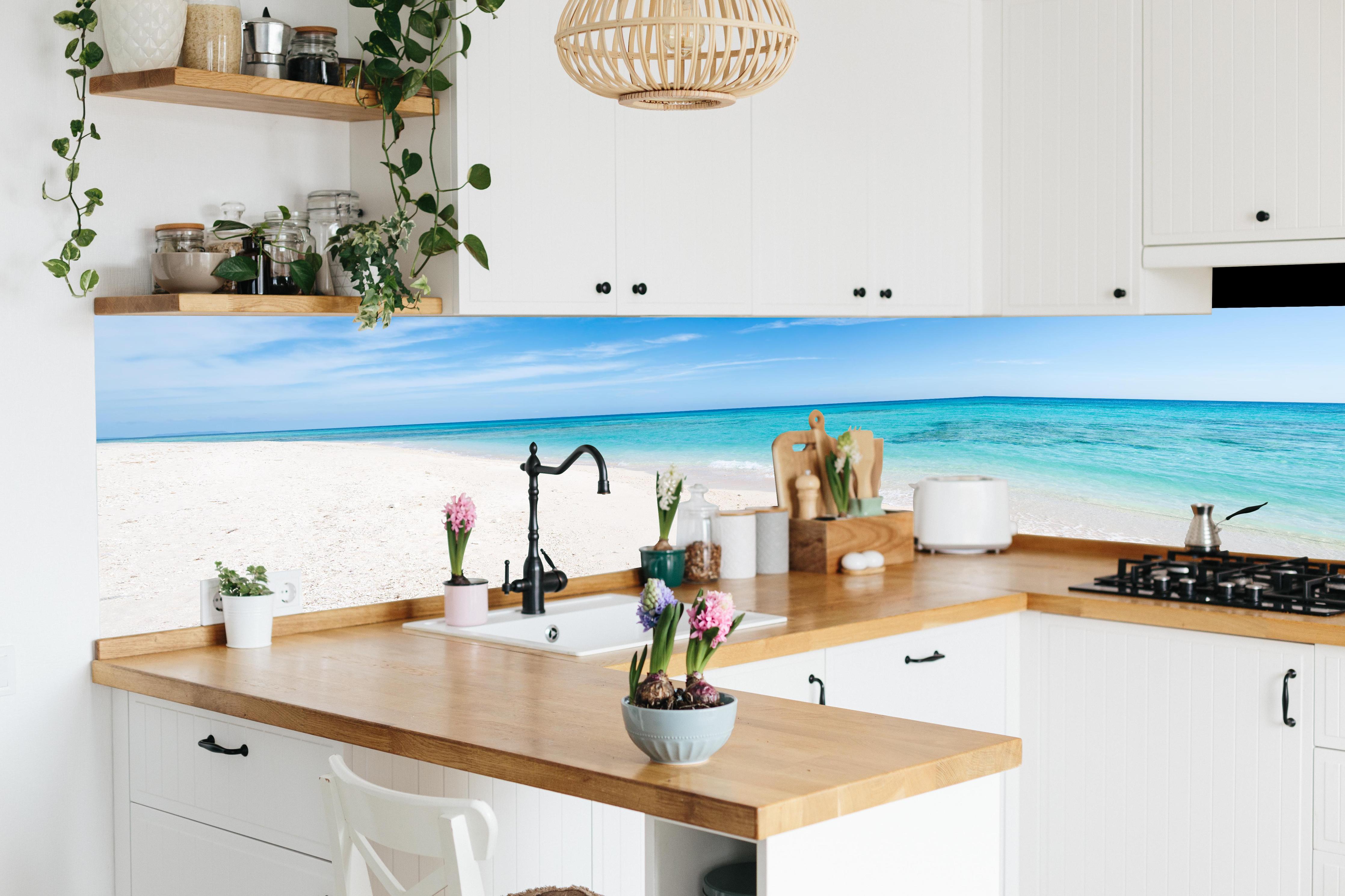 Küche - Idyllischer karibischer Strand mit strahlend blauem Wasser und feinem Sand hinter weißen Hochglanz-Küchenregalen und schwarzem Wasserhahn