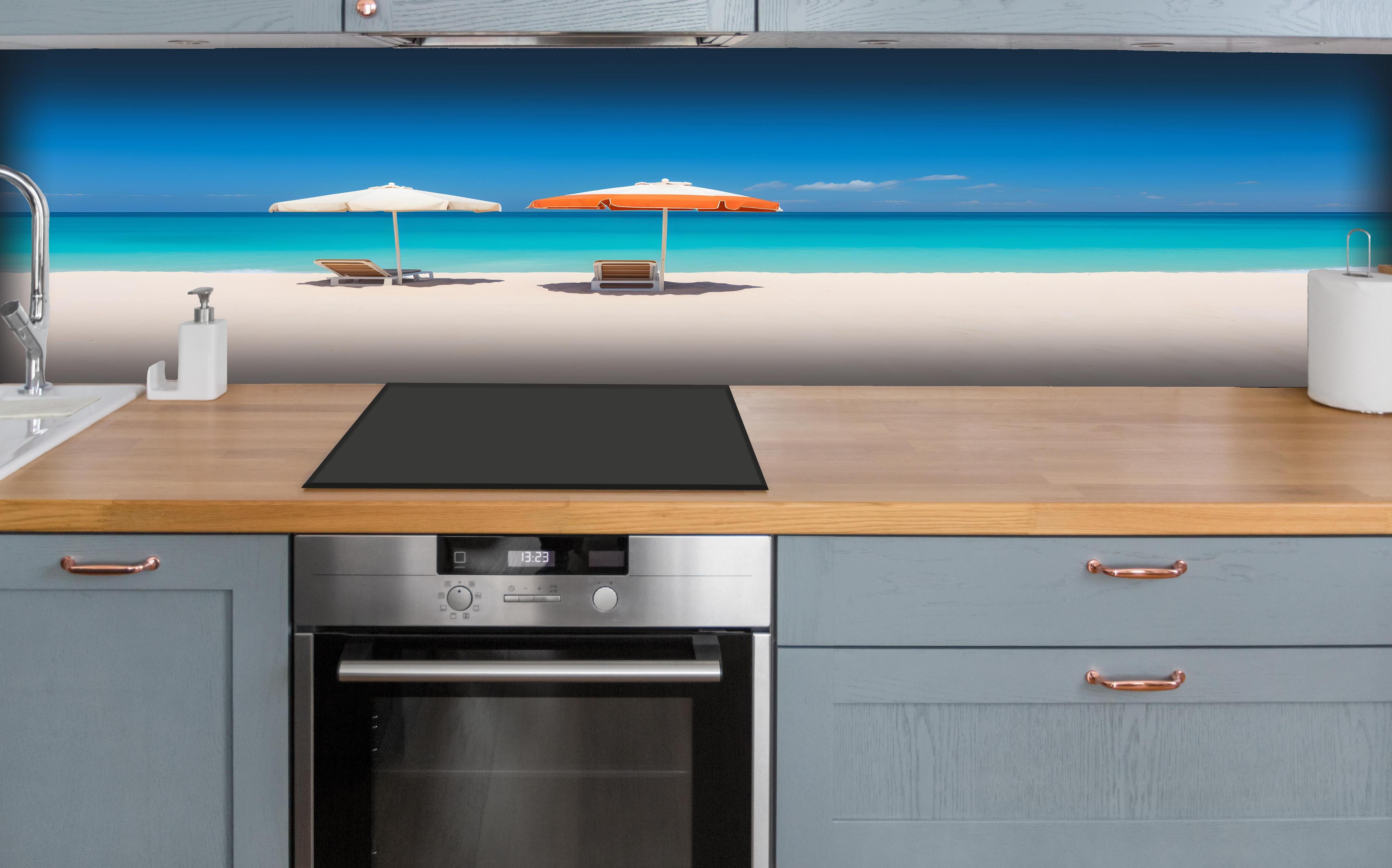 Küche - Idyllischer tropischer Strand mit weißen Sand und sonnigen Schirmen hinter weißen Hochglanz-Küchenregalen und schwarzem Wasserhahn