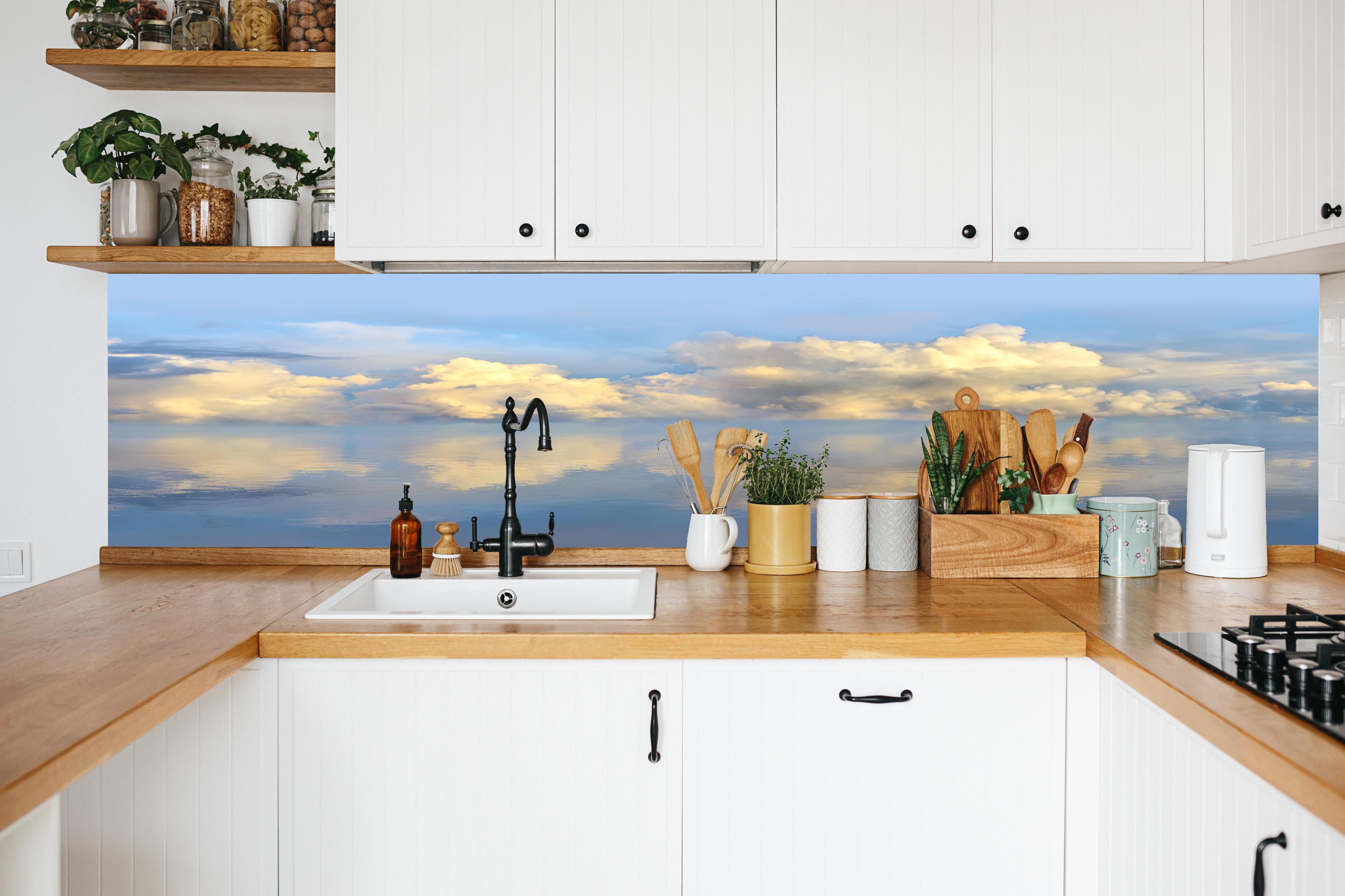 Küche - Idyllisches Wolkenmeer mit leuchtenden Reflexionen auf ruhigem Wasser hinter weißen Hochglanz-Küchenregalen und schwarzem Wasserhahn