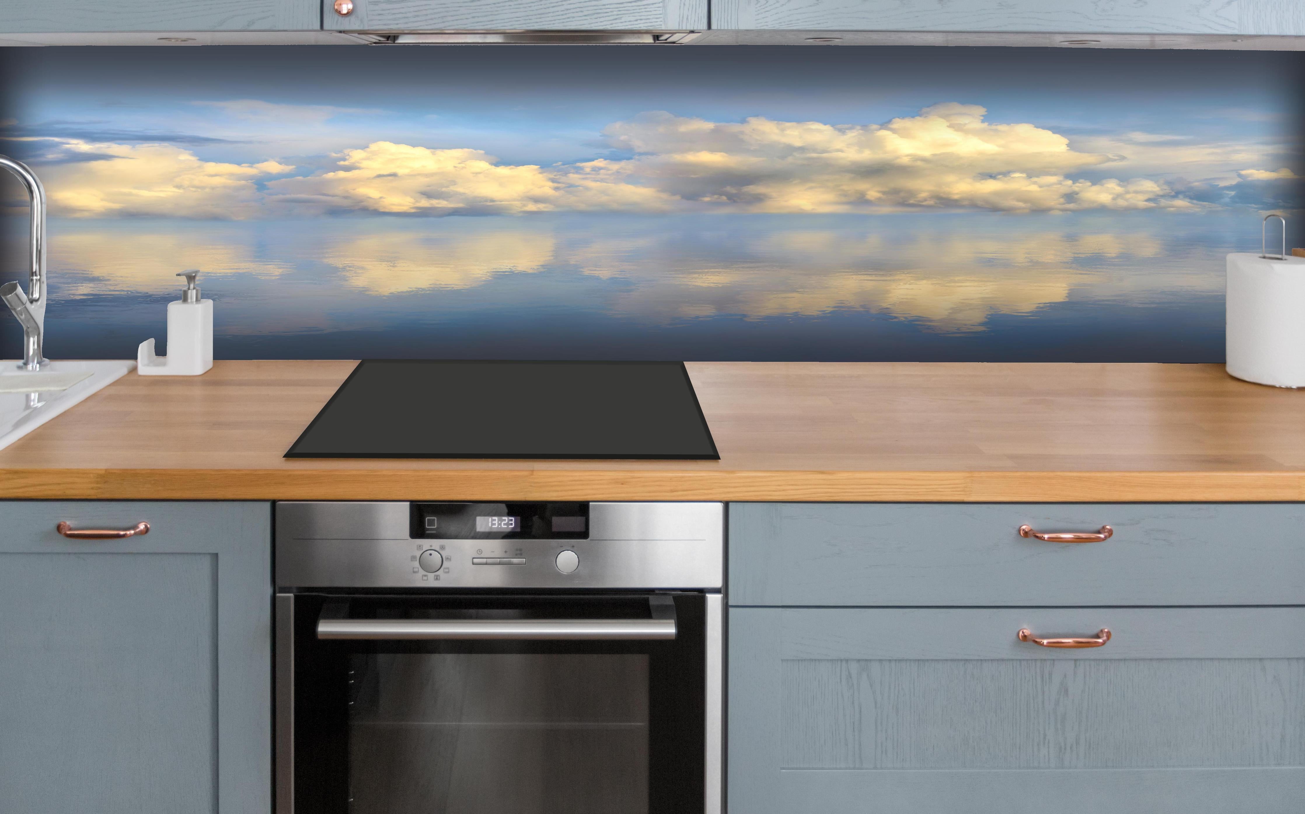 Küche - Idyllisches Wolkenmeer mit leuchtenden Reflexionen auf ruhigem Wasser hinter weißen Hochglanz-Küchenregalen und schwarzem Wasserhahn