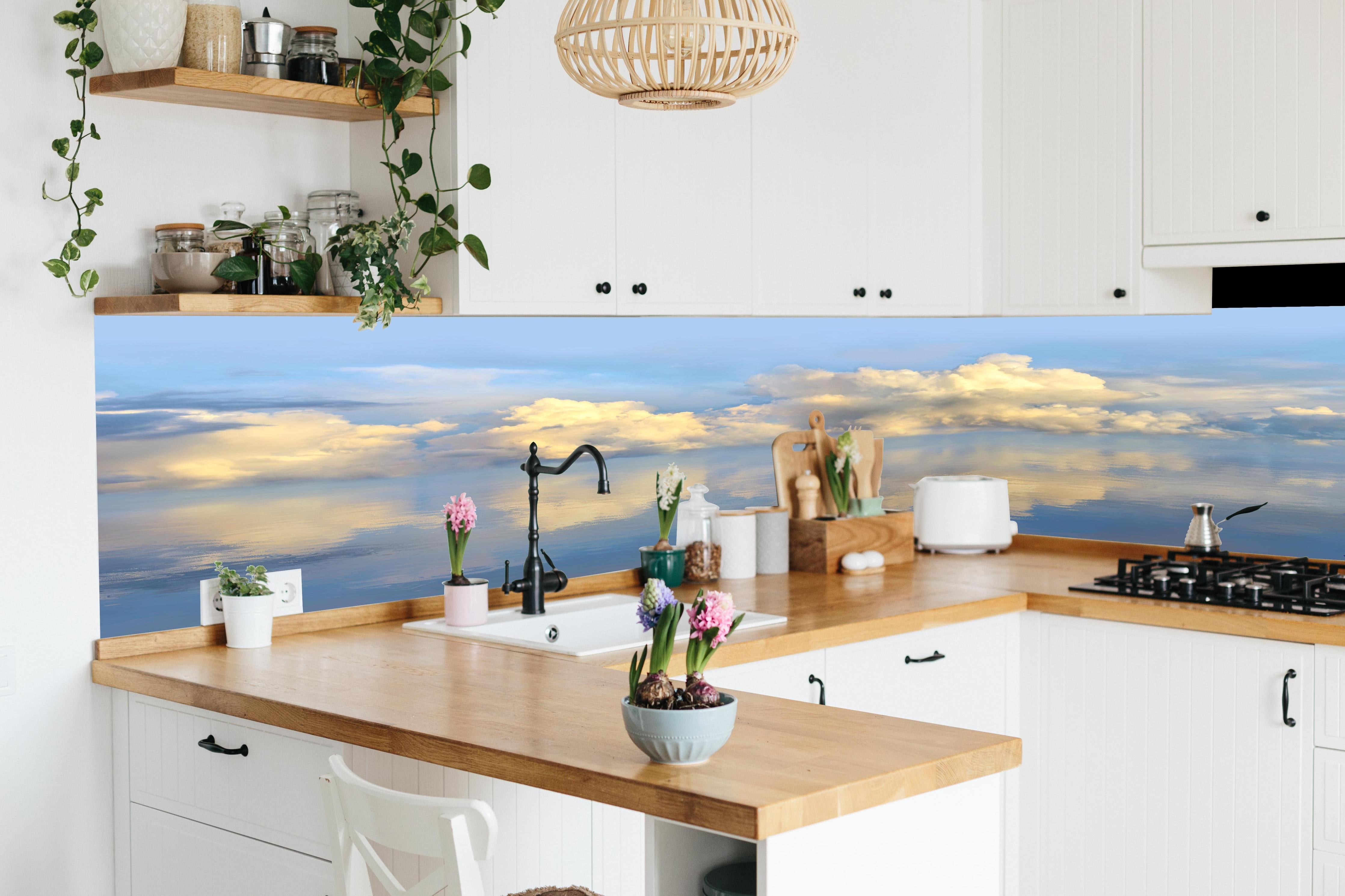 Küche - Idyllisches Wolkenmeer mit leuchtenden Reflexionen auf ruhigem Wasser hinter weißen Hochglanz-Küchenregalen und schwarzem Wasserhahn
