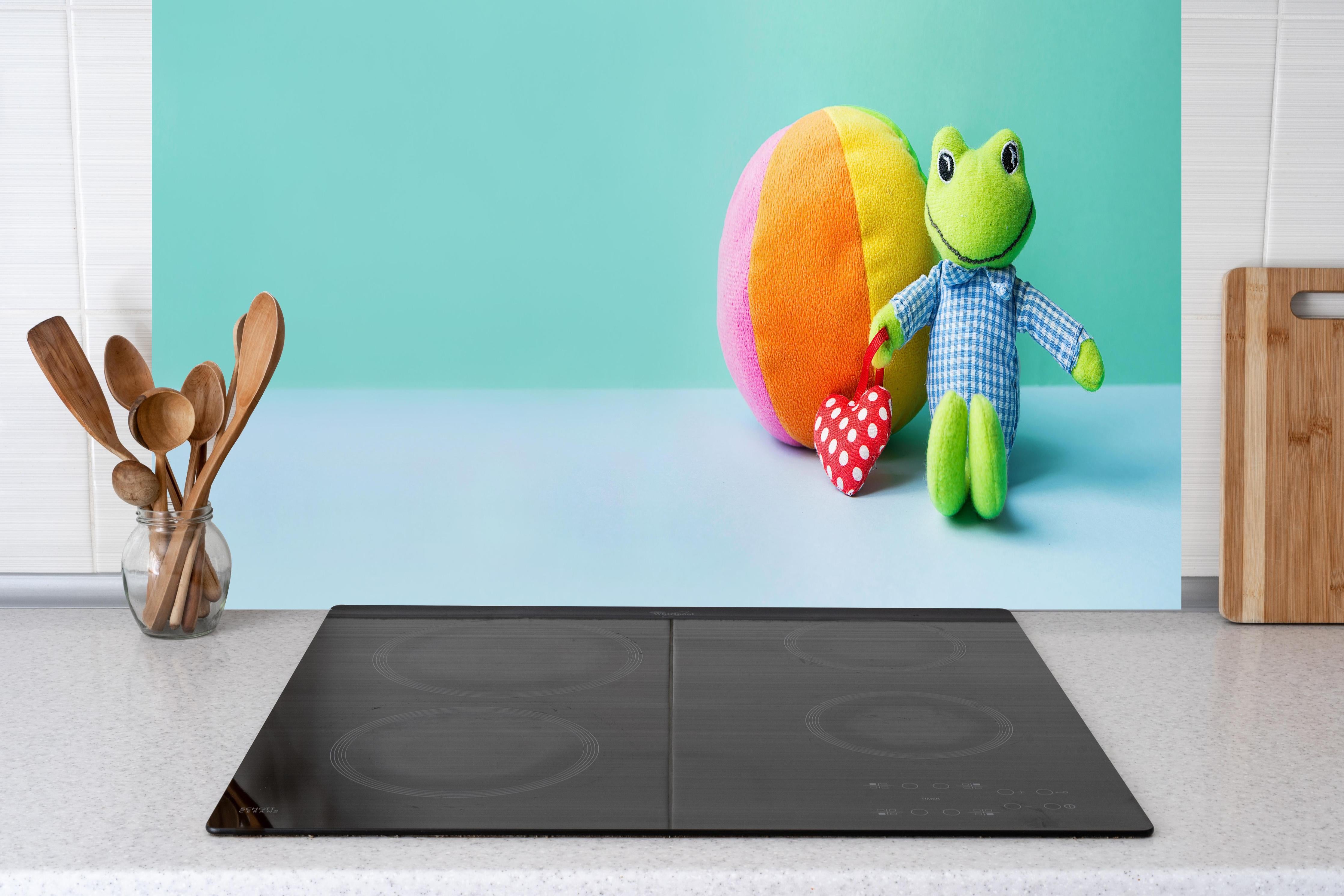 Küche - Kinderspielzeug Kleiner Frosch hinter weißen Hochglanz-Küchenregalen und schwarzem Wasserhahn