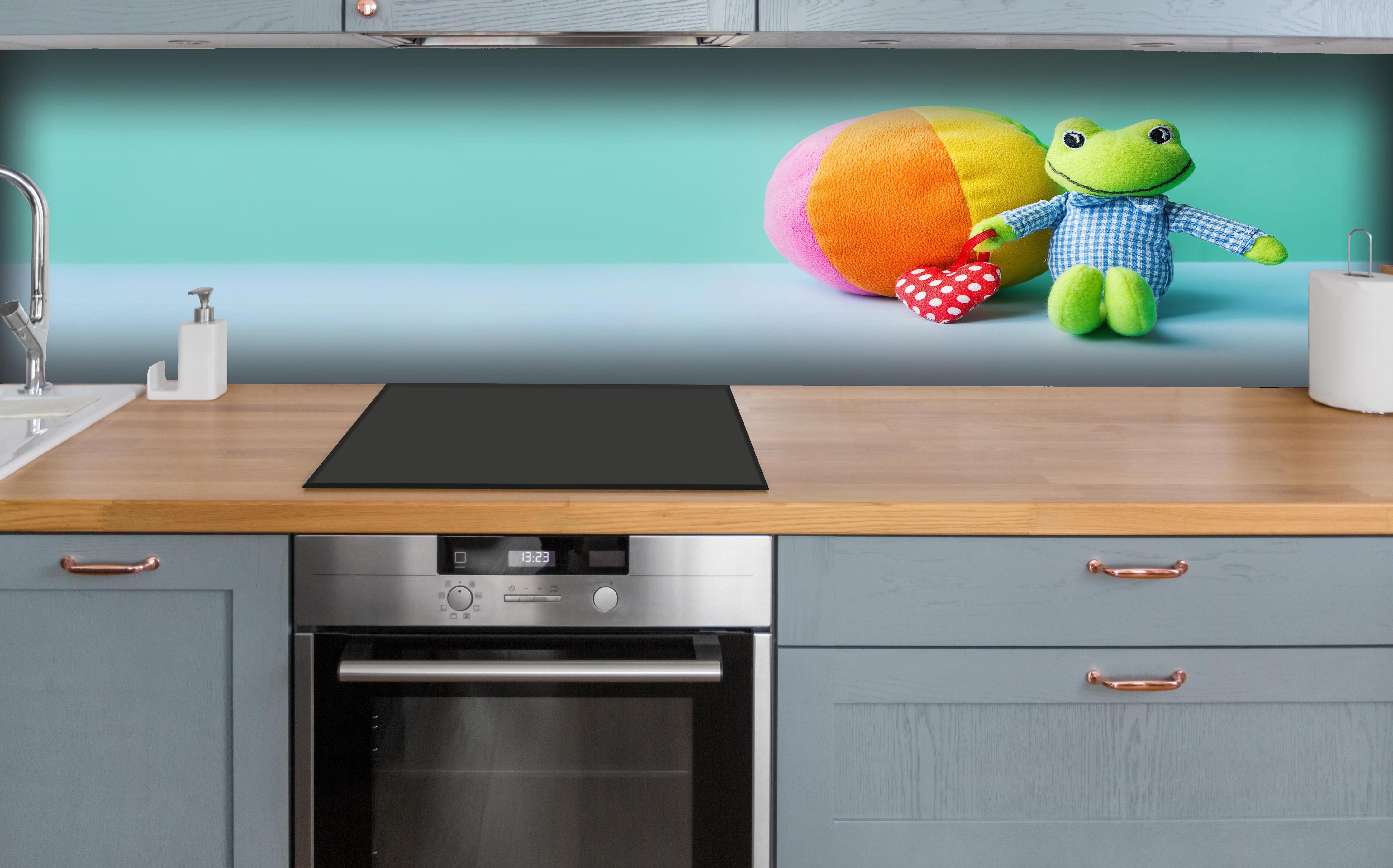 Küche - Kinderspielzeug Kleiner Frosch hinter weißen Hochglanz-Küchenregalen und schwarzem Wasserhahn