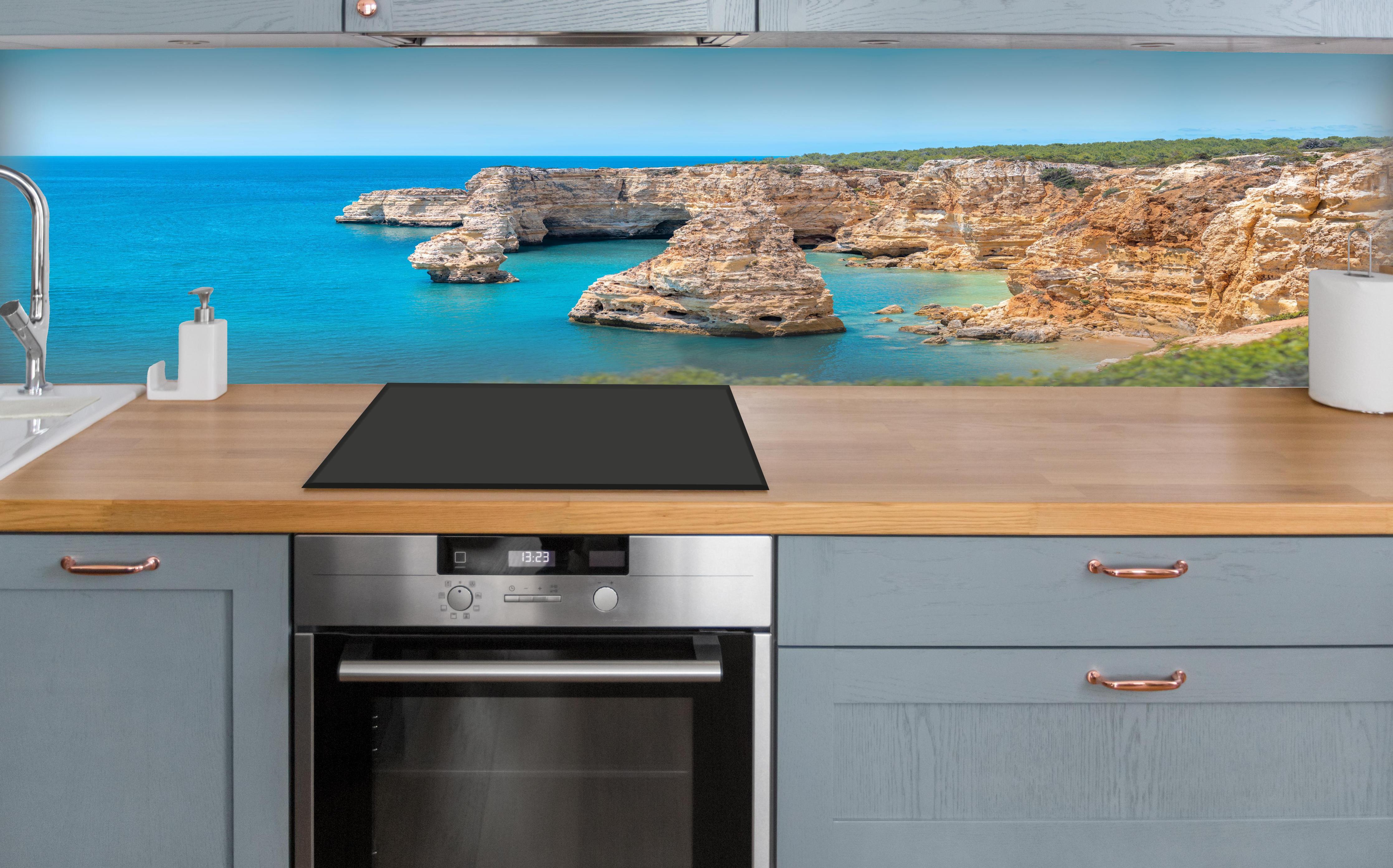 Küche - Algarve-Klippen am türkisblauen Meer über polierter Holzarbeitsplatte mit Cerankochfeld