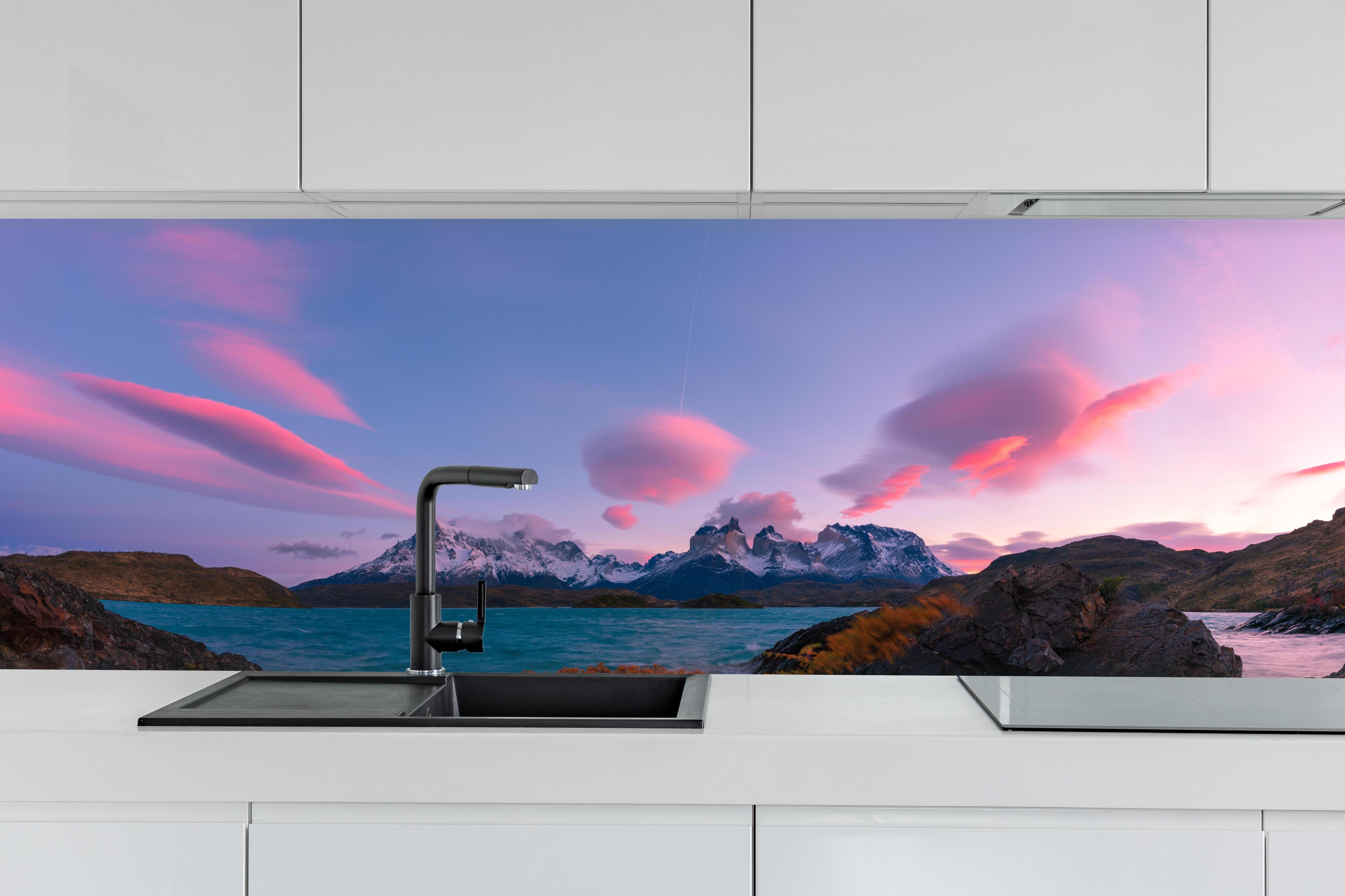 Küche - Bergpanorama im rosa Sonnenuntergang hinter weißen Hochglanz-Küchenregalen und schwarzem Wasserhahn