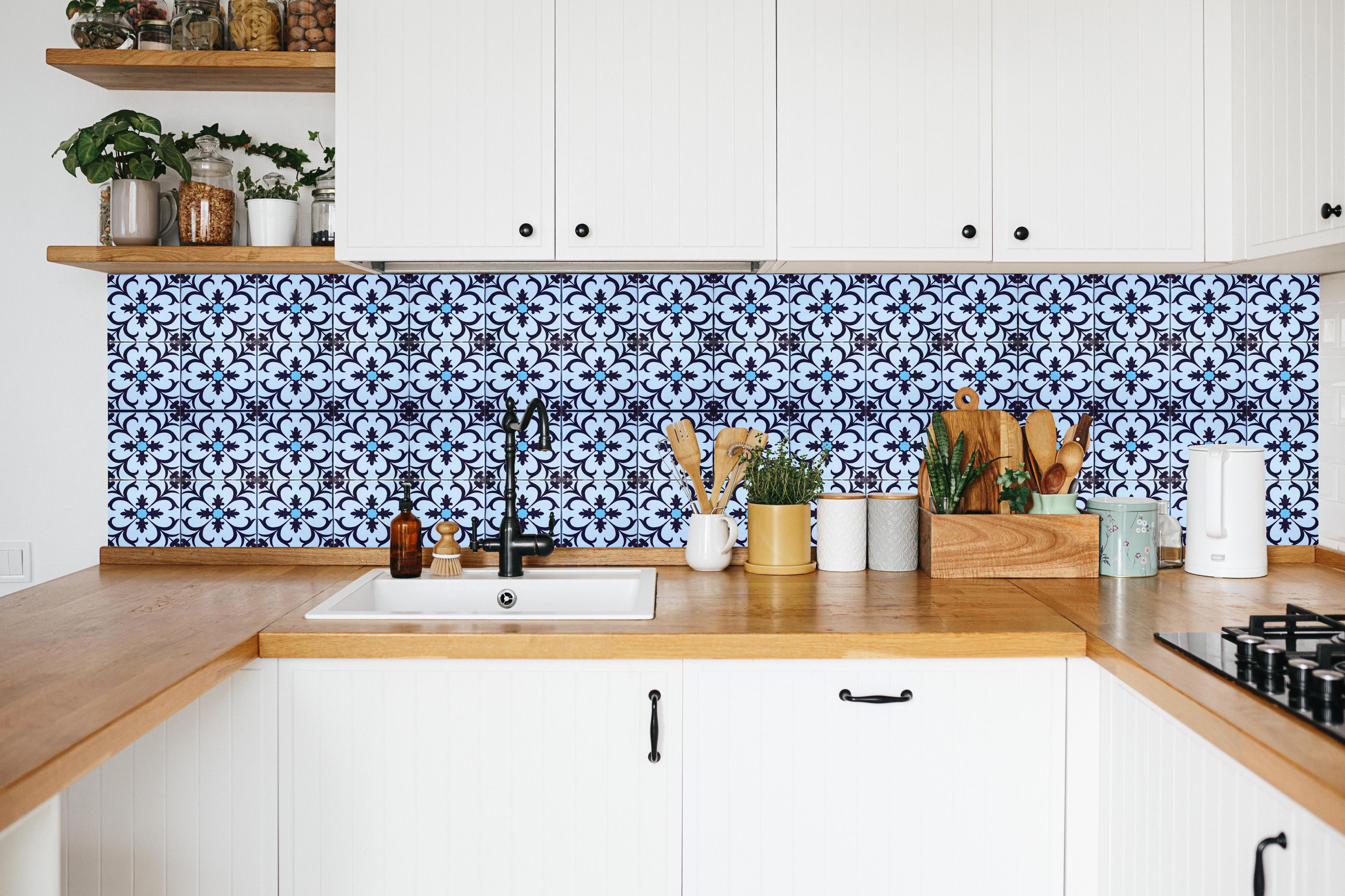 Küche - Blau-Weiße Vintage-Kachelfliesen in weißer Küche hinter Gewürzen und Kochlöffeln aus Holz