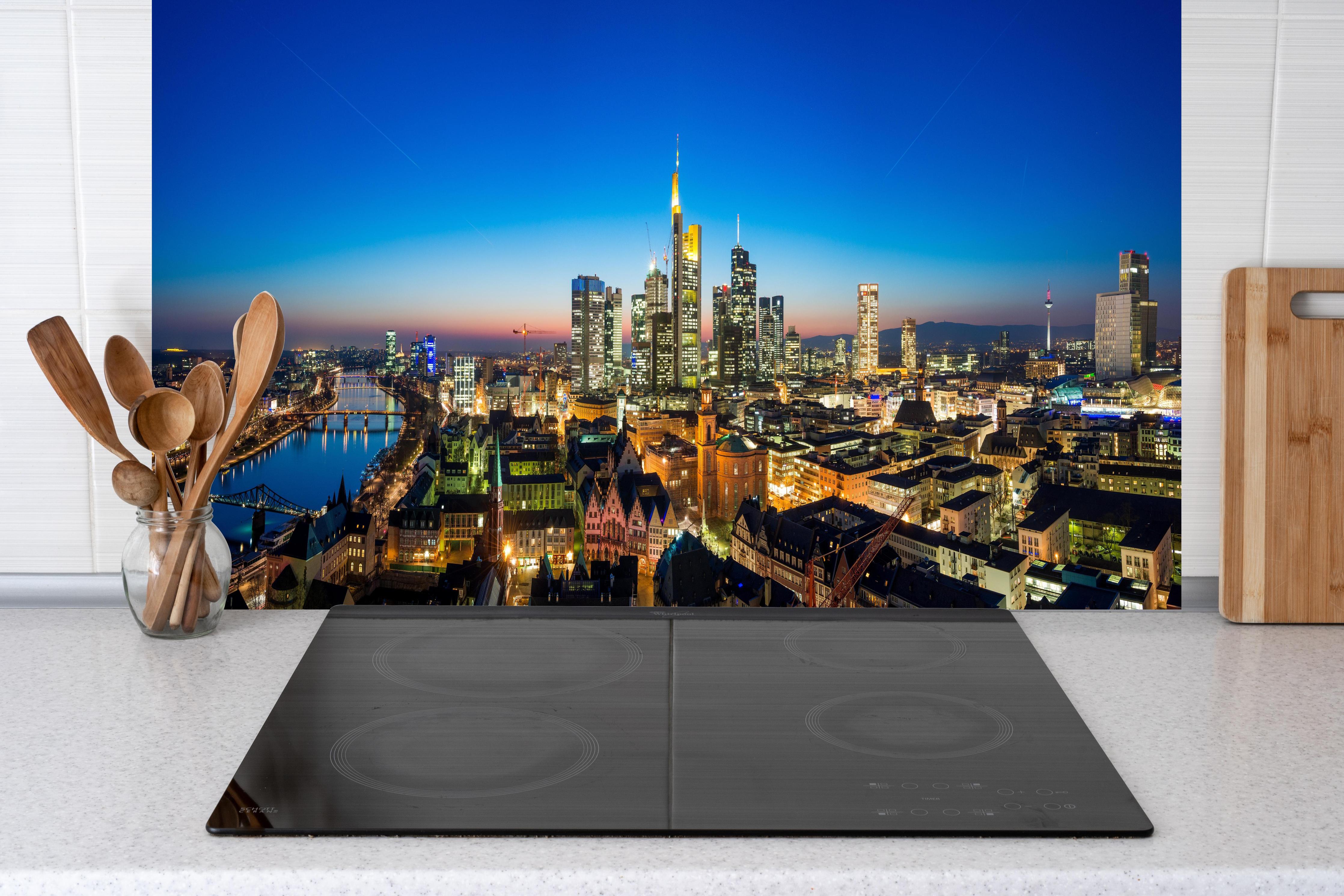 Küche - Blaue Skyline bei Abenddämmerung hinter Cerankochfeld und Holz-Kochutensilien