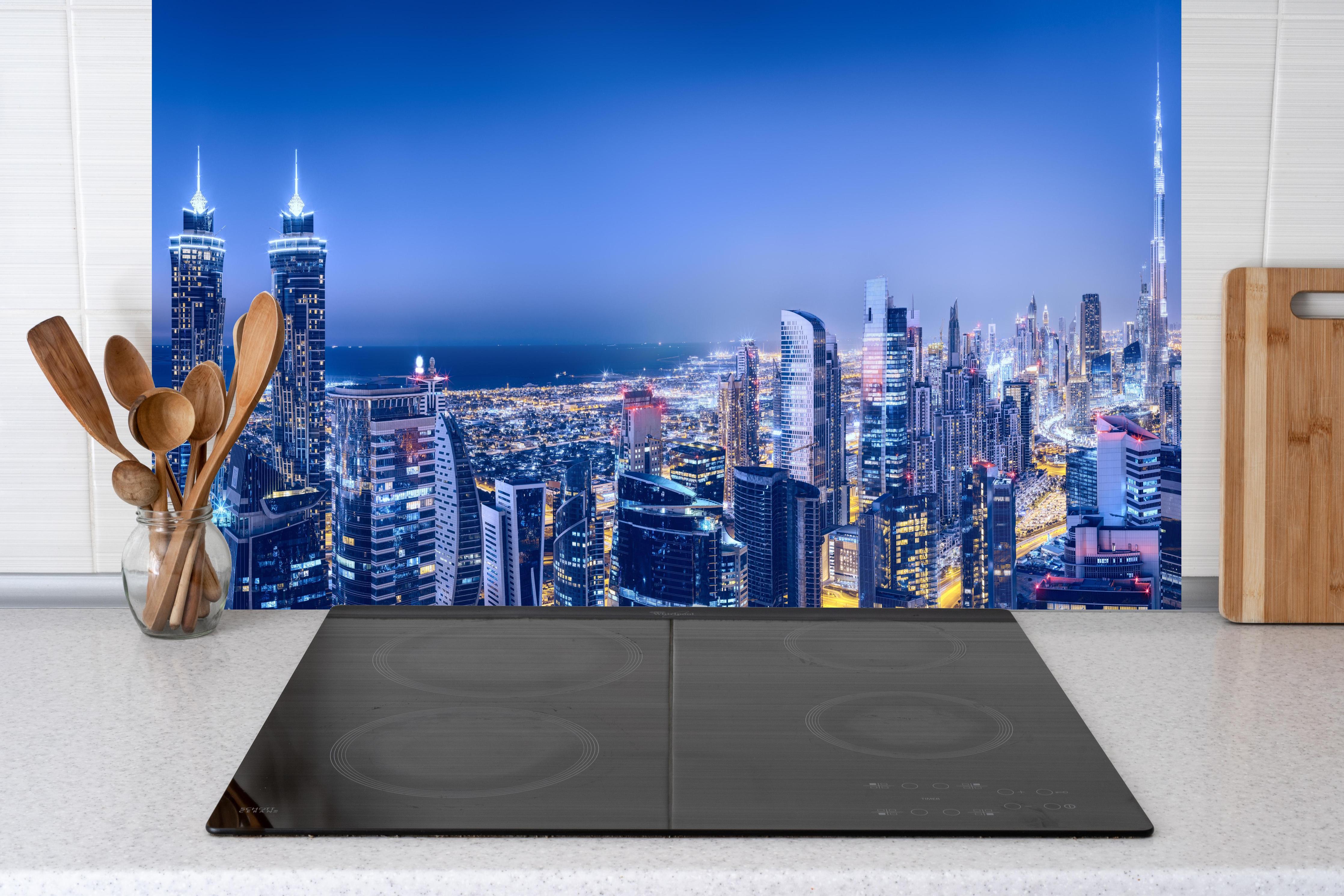 Küche - Blaue Skyline bei Nacht hinter Cerankochfeld und Holz-Kochutensilien