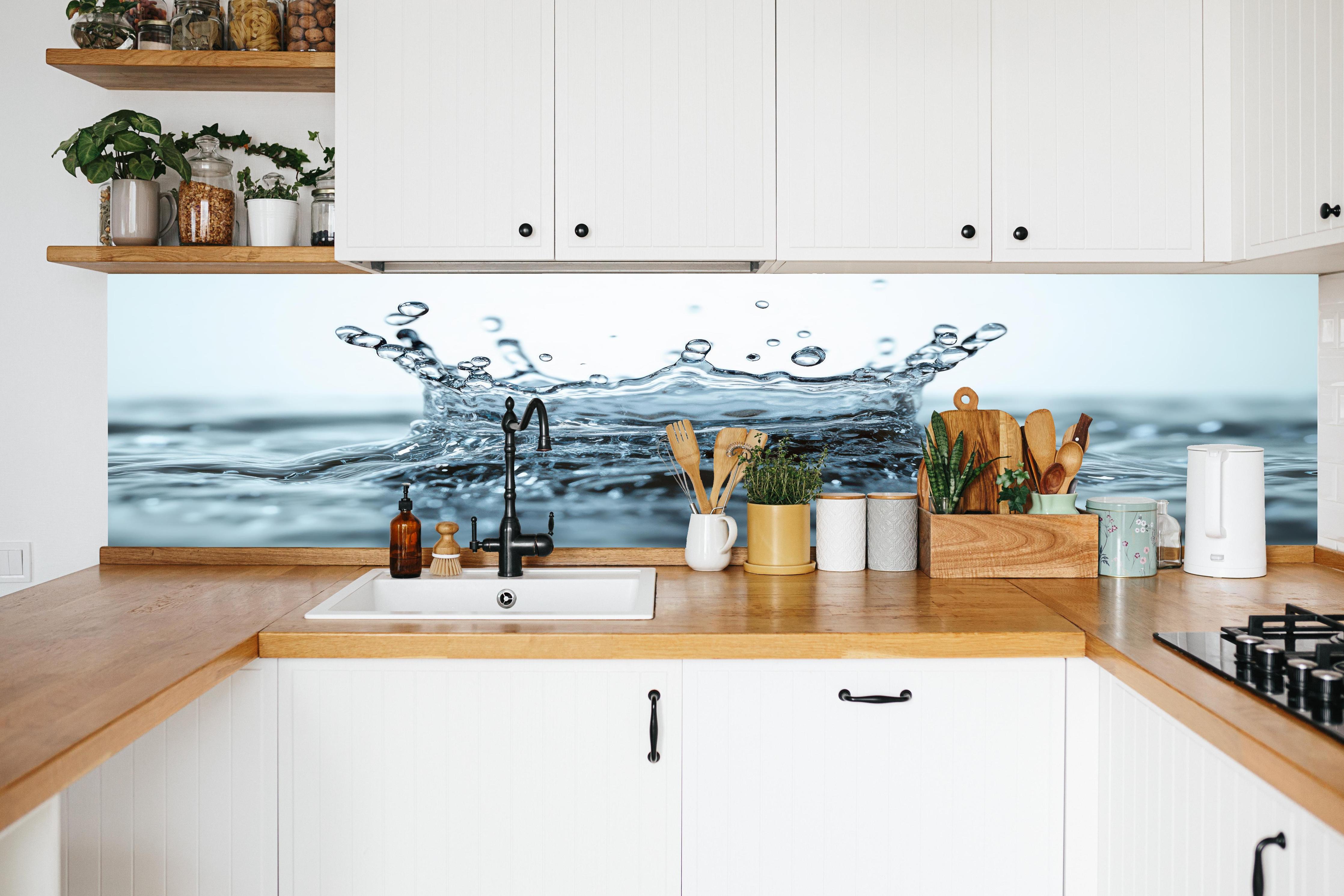 Küche - Blauer Wasser-Splash in weißer Küche hinter Gewürzen und Kochlöffeln aus Holz