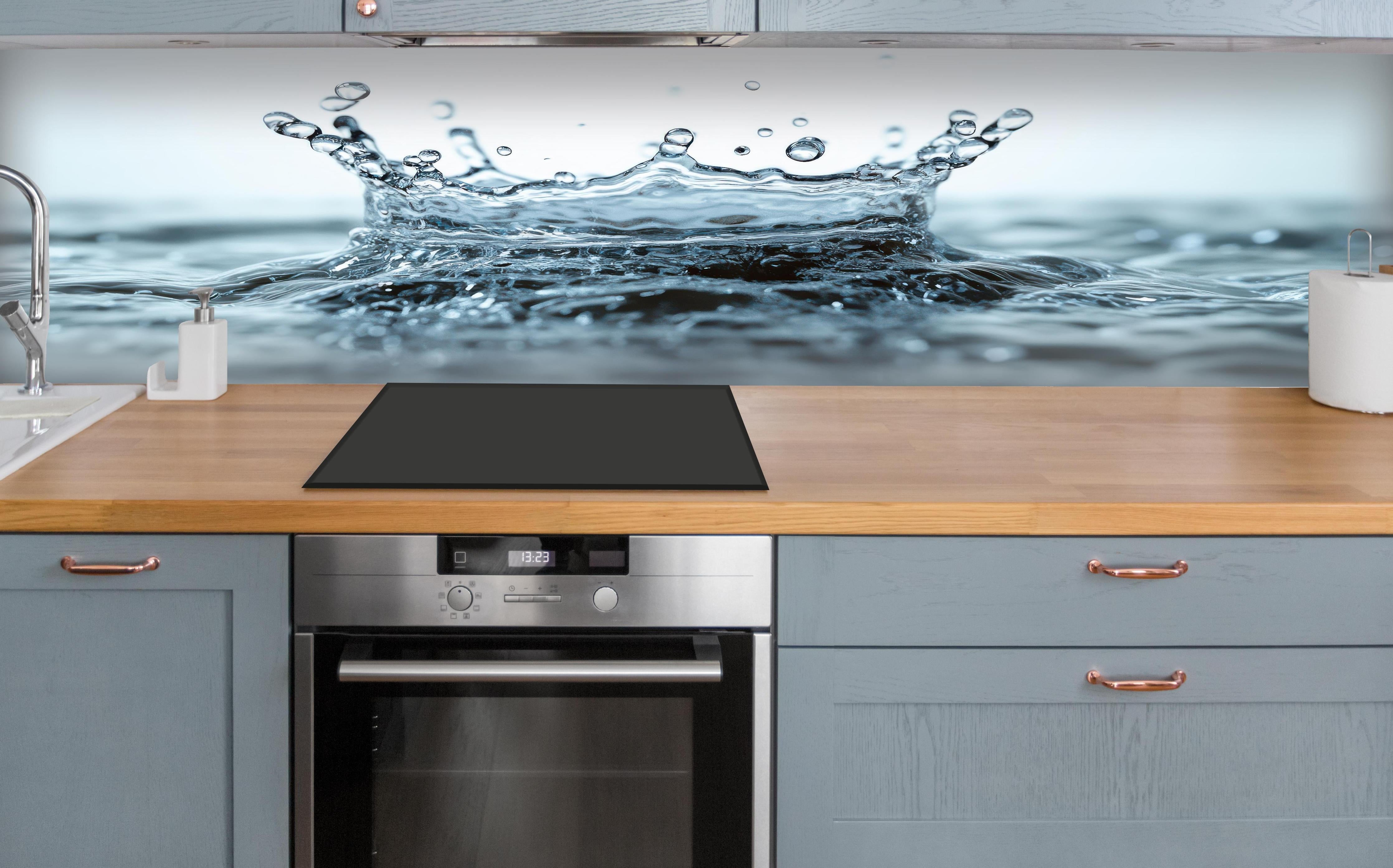 Küche - Blauer Wasser-Splash über polierter Holzarbeitsplatte mit Cerankochfeld