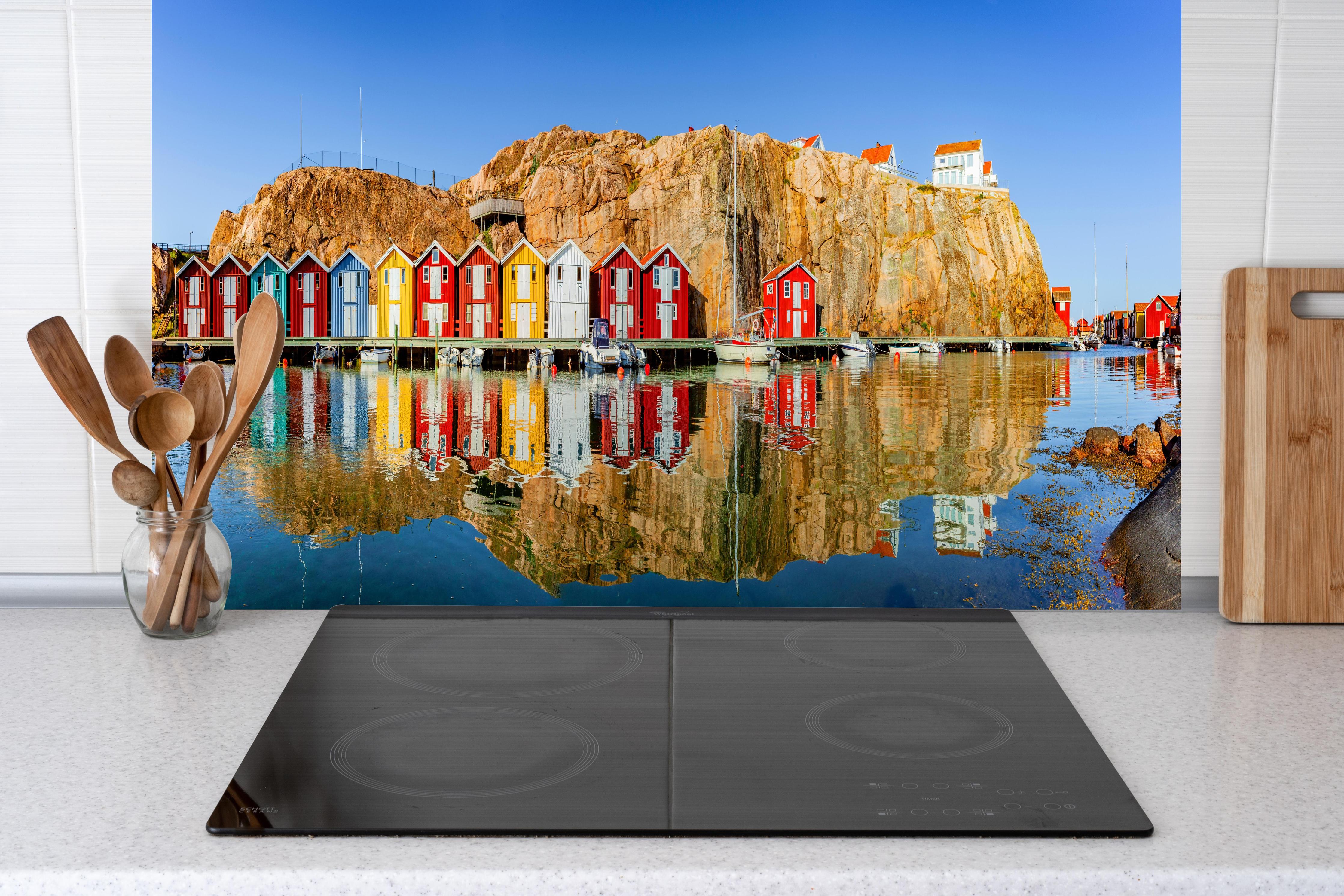 Küche - Bunte Fischerhäuser in Schweden hinter Cerankochfeld und Holz-Kochutensilien