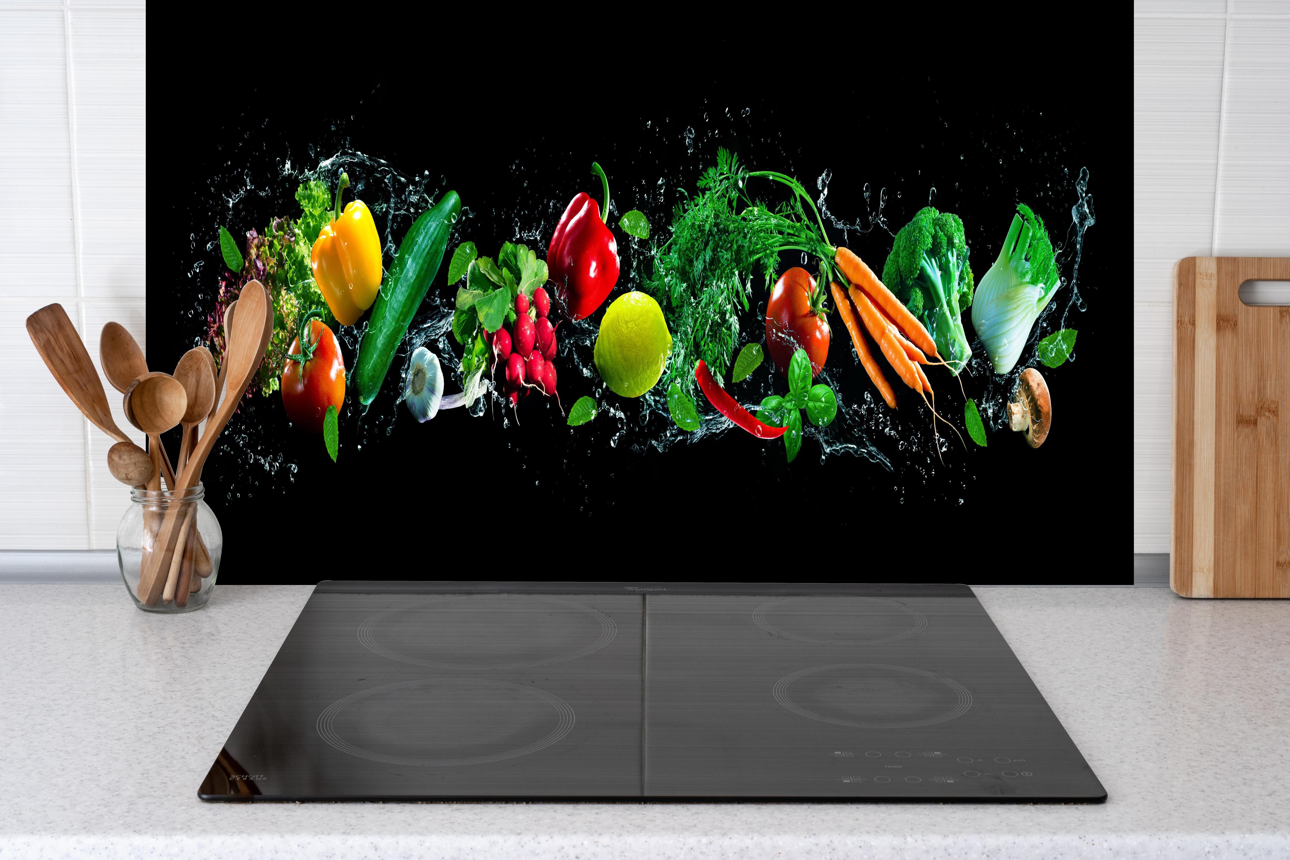 Küche - Buntes Obst auf schwarzem Hintergrund hinter Cerankochfeld und Holz-Kochutensilien
