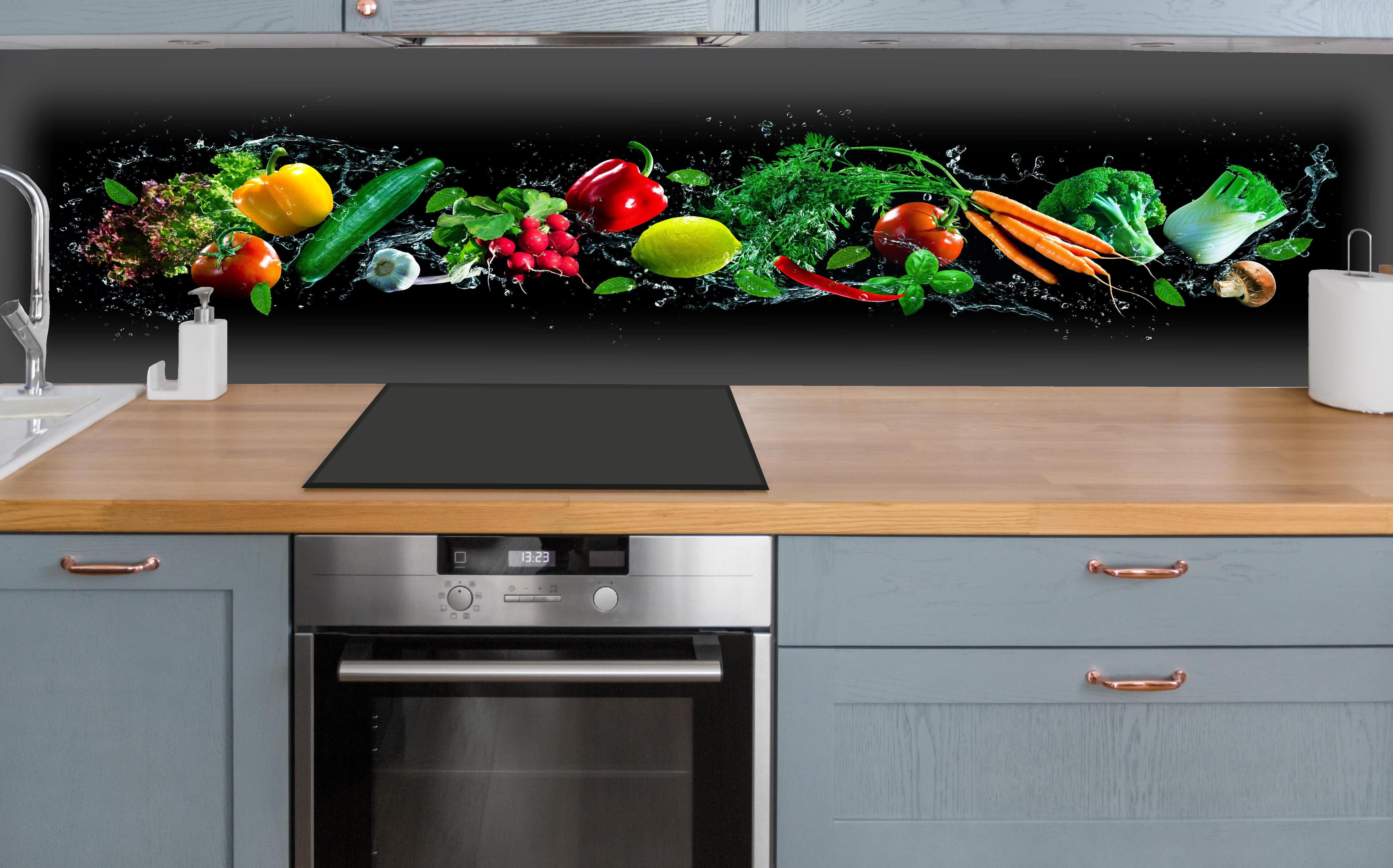 Küche - Buntes Obst auf schwarzem Hintergrund über polierter Holzarbeitsplatte mit Cerankochfeld