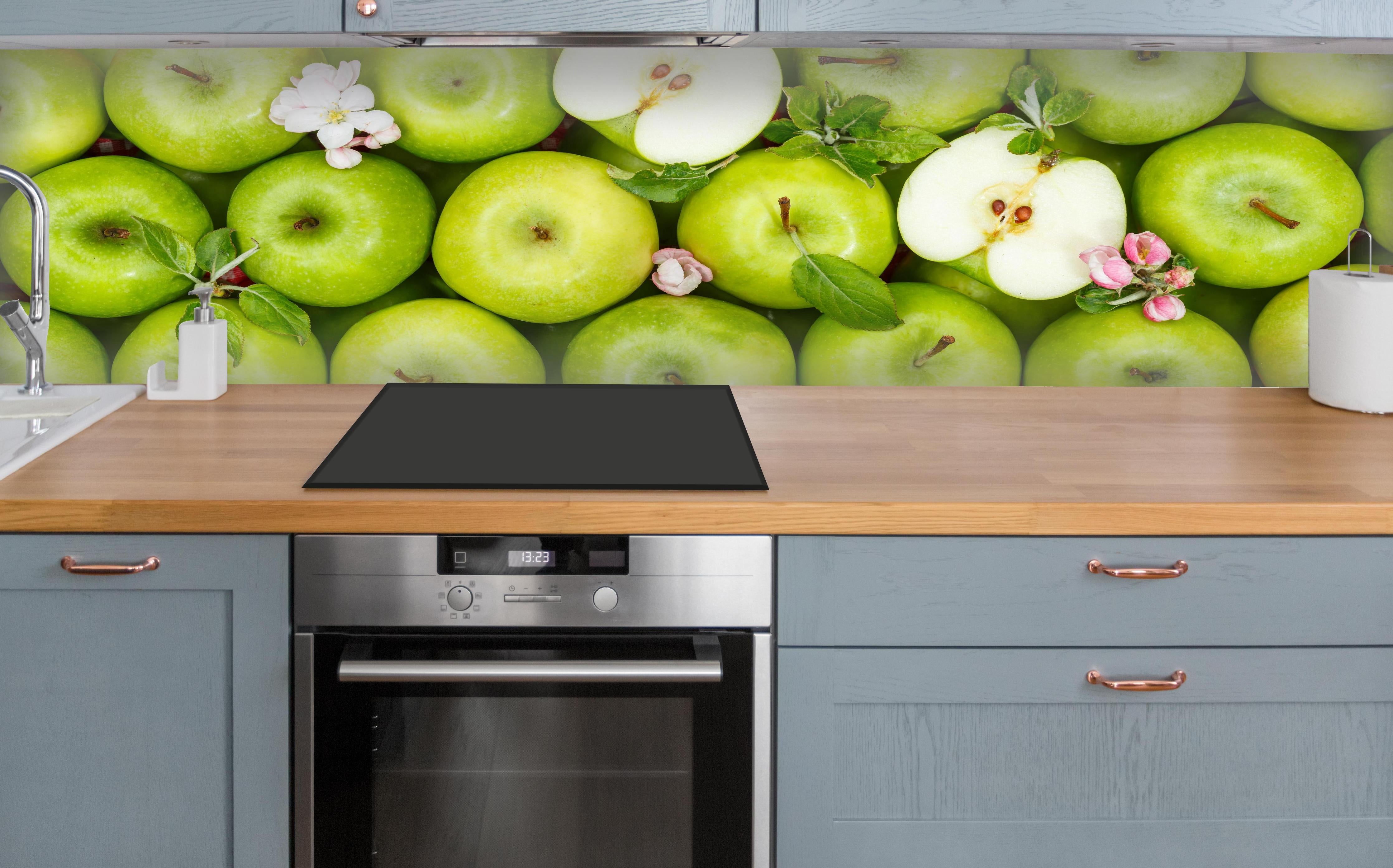 Küche - Frische grüne Äpfel über polierter Holzarbeitsplatte mit Cerankochfeld