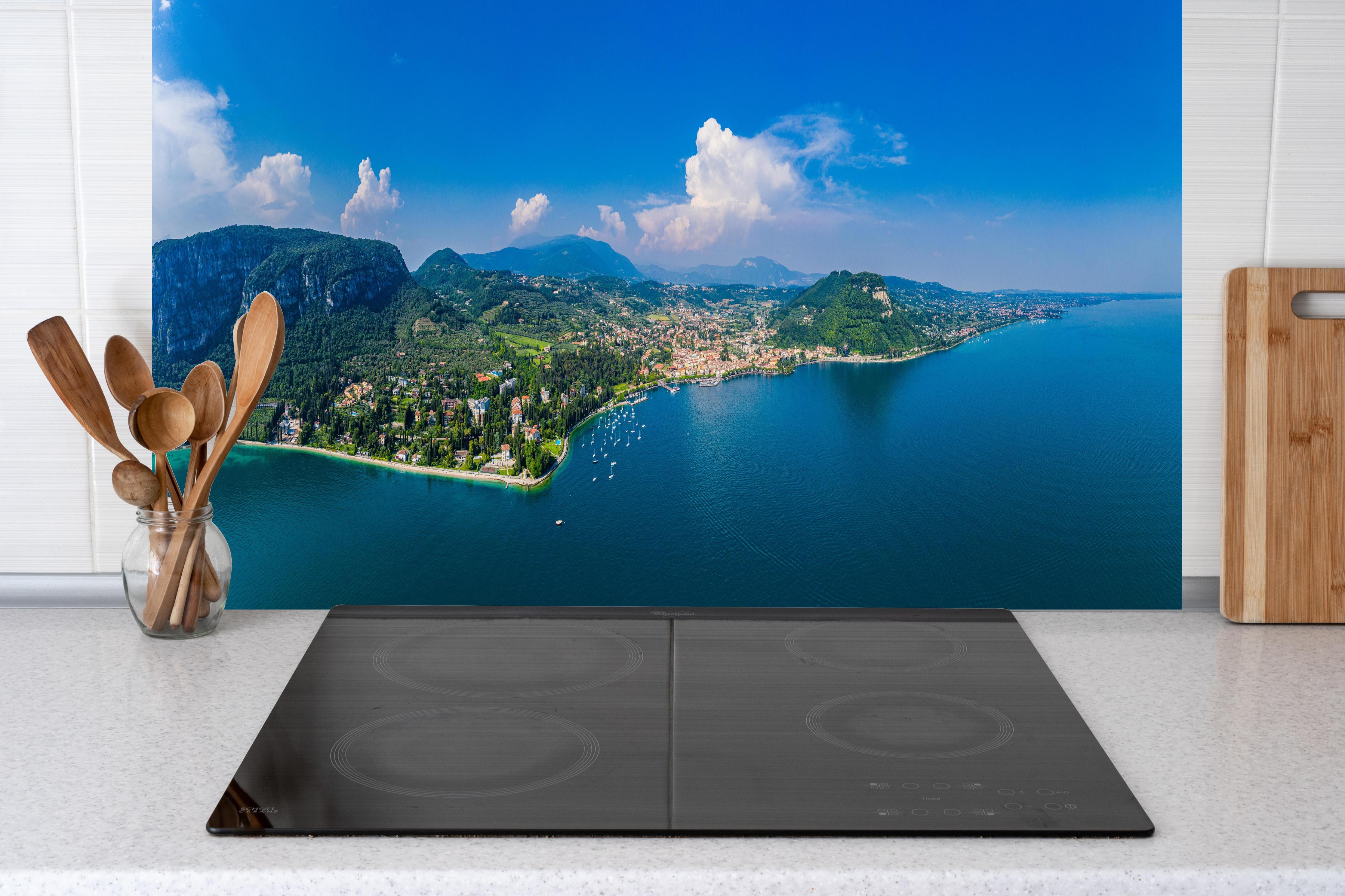 Küche - Gardasee Panorama Blau-Grün hinter Cerankochfeld und Holz-Kochutensilien