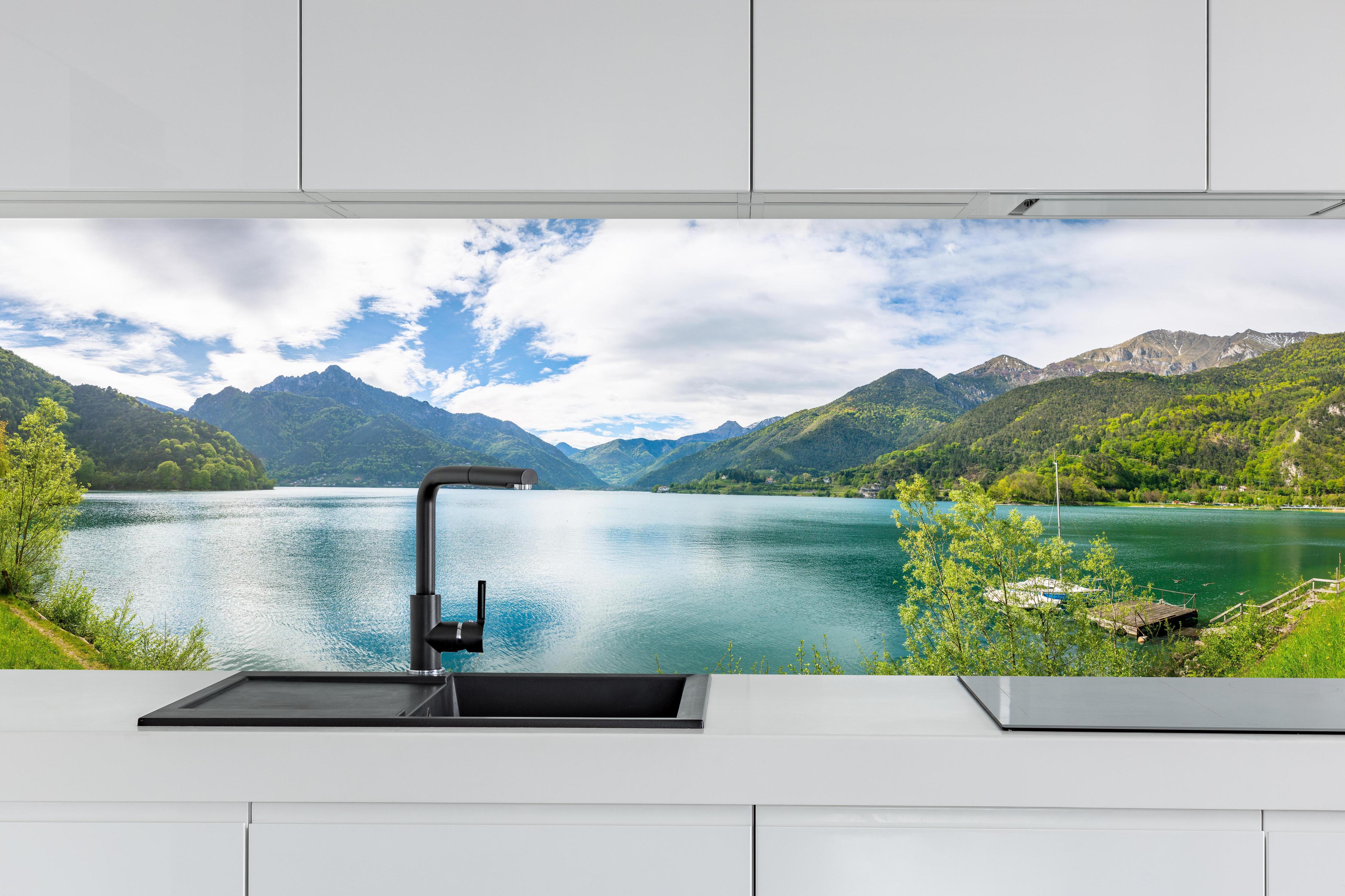 Küche - Gardasee Türkis-Grünes Panorama hinter weißen Hochglanz-Küchenregalen und schwarzem Wasserhahn