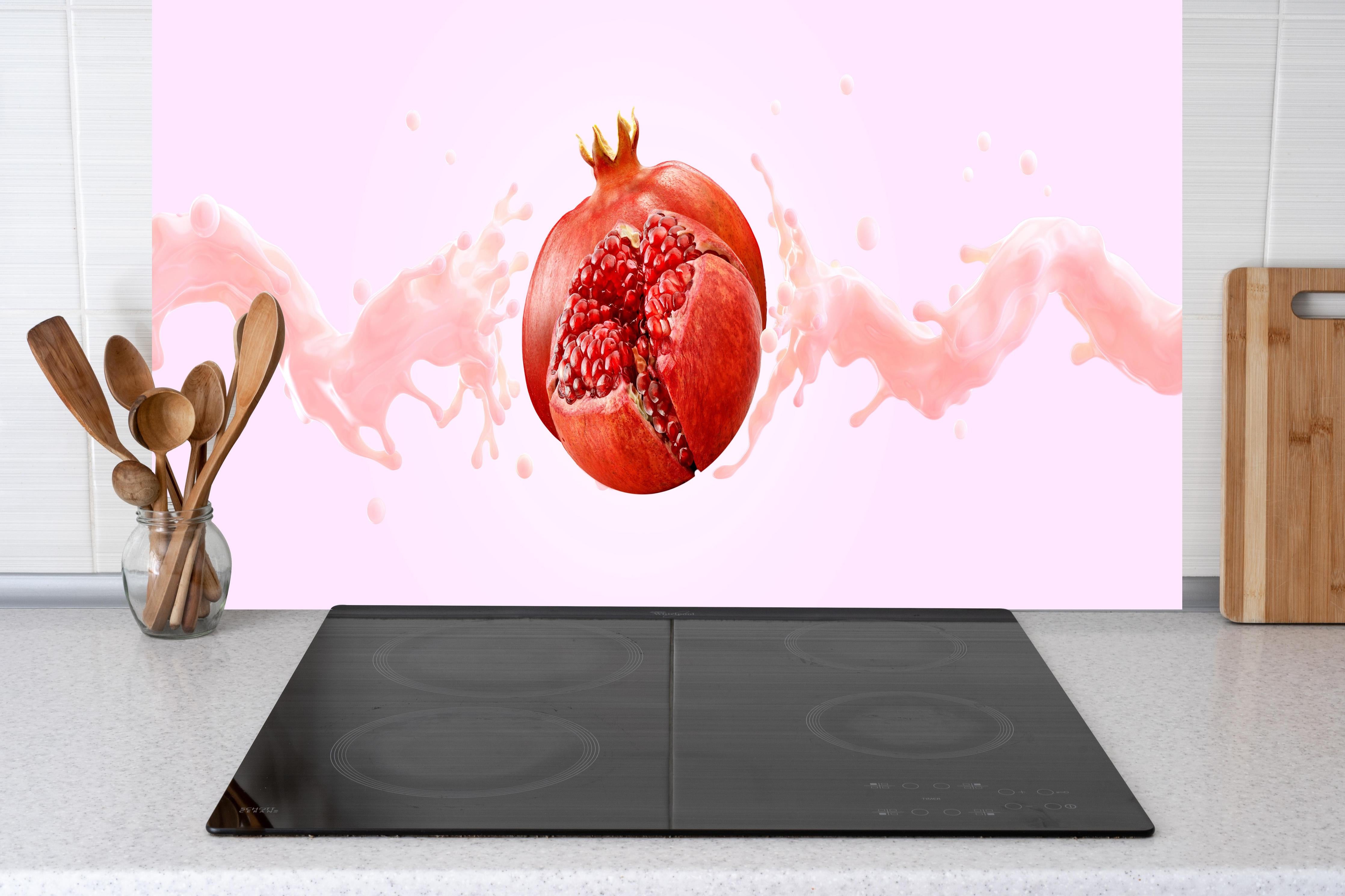 Küche - Granatapfel mit rosa Milch-Splash hinter Cerankochfeld und Holz-Kochutensilien