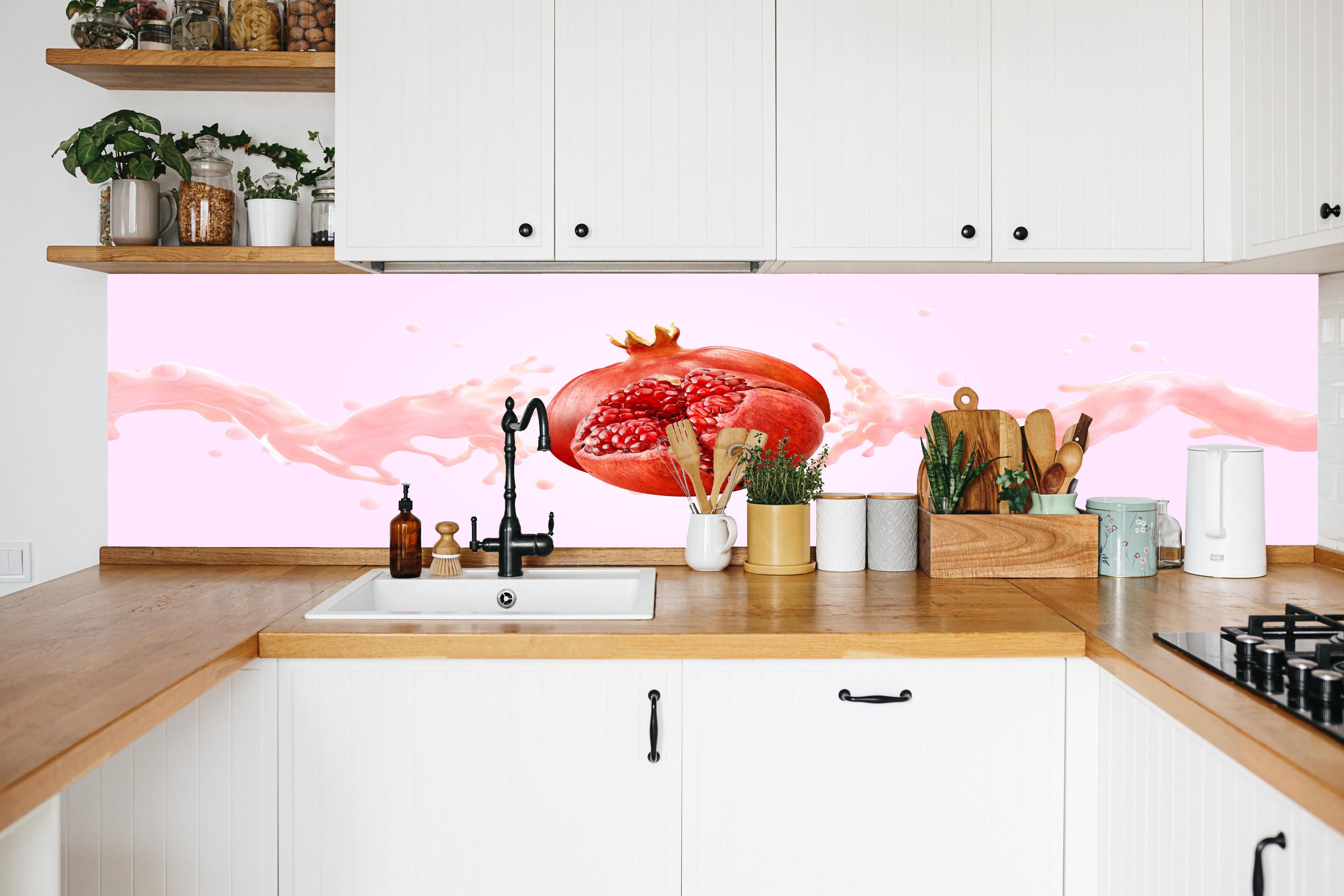 Küche - Granatapfel mit rosa Milch-Splash in weißer Küche hinter Gewürzen und Kochlöffeln aus Holz