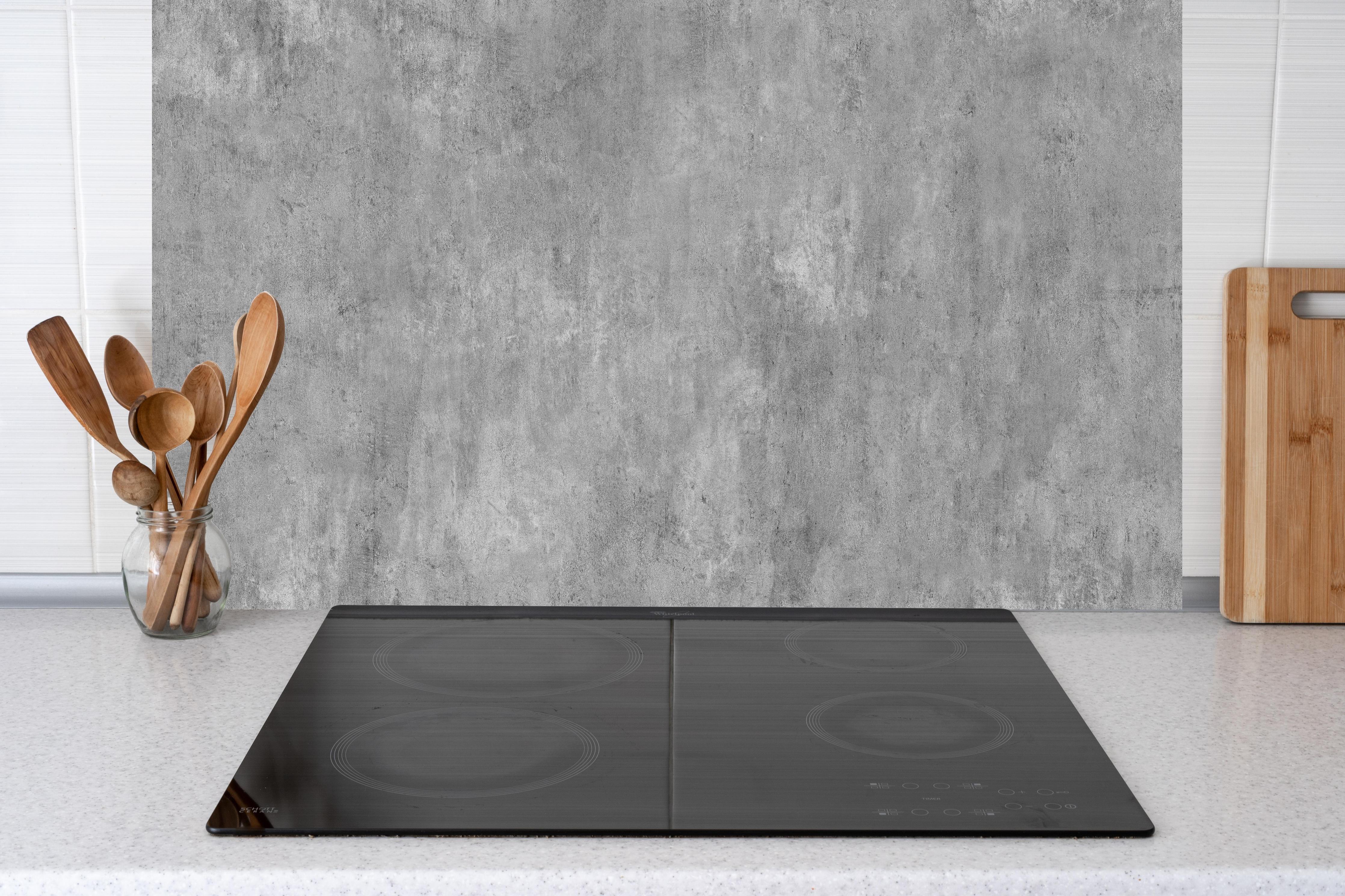 Küche - Grau-Weiß Betonstruktur hinter Cerankochfeld und Holz-Kochutensilien