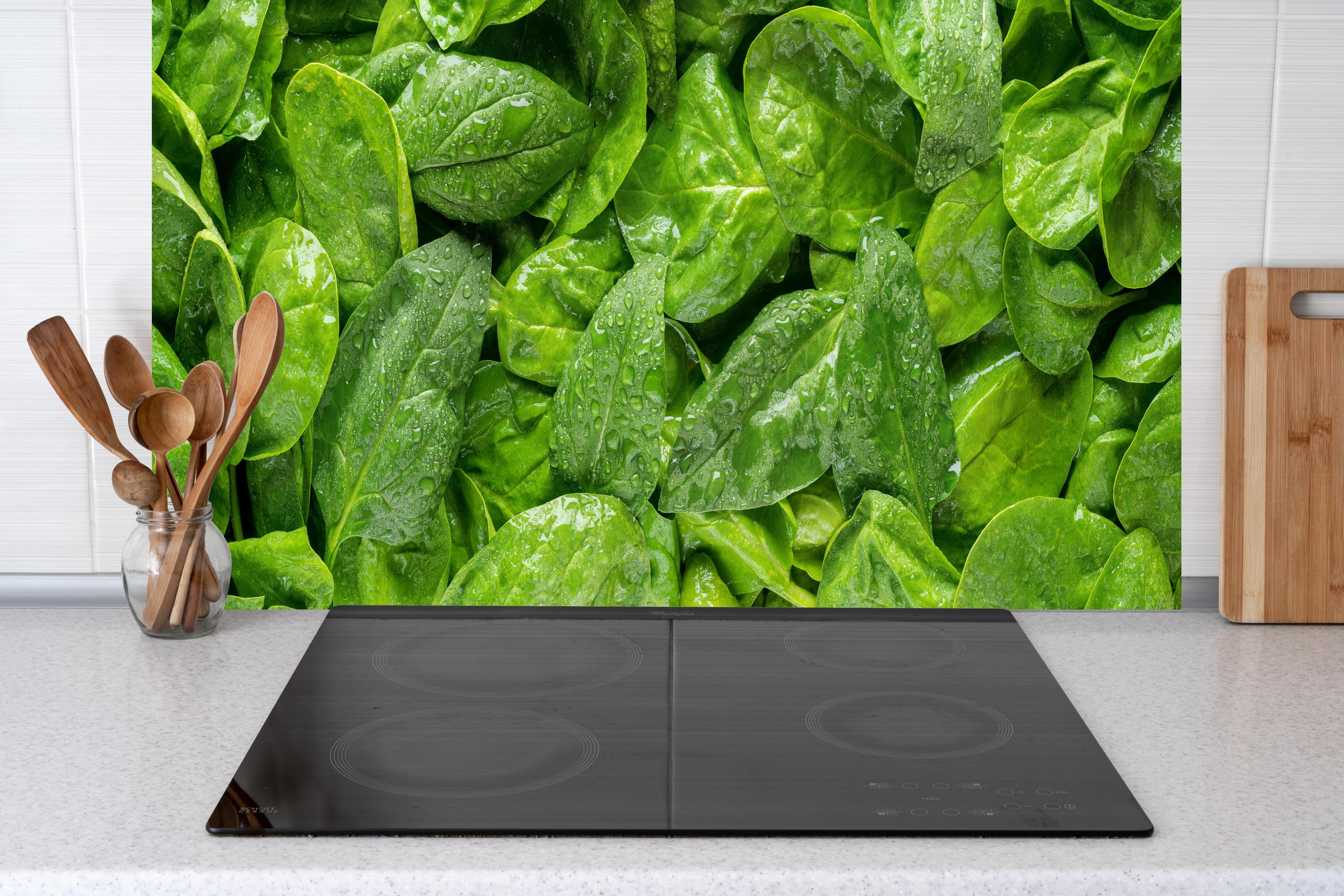 Küche - Grünes Kräuterblatt-Muster hinter Cerankochfeld und Holz-Kochutensilien