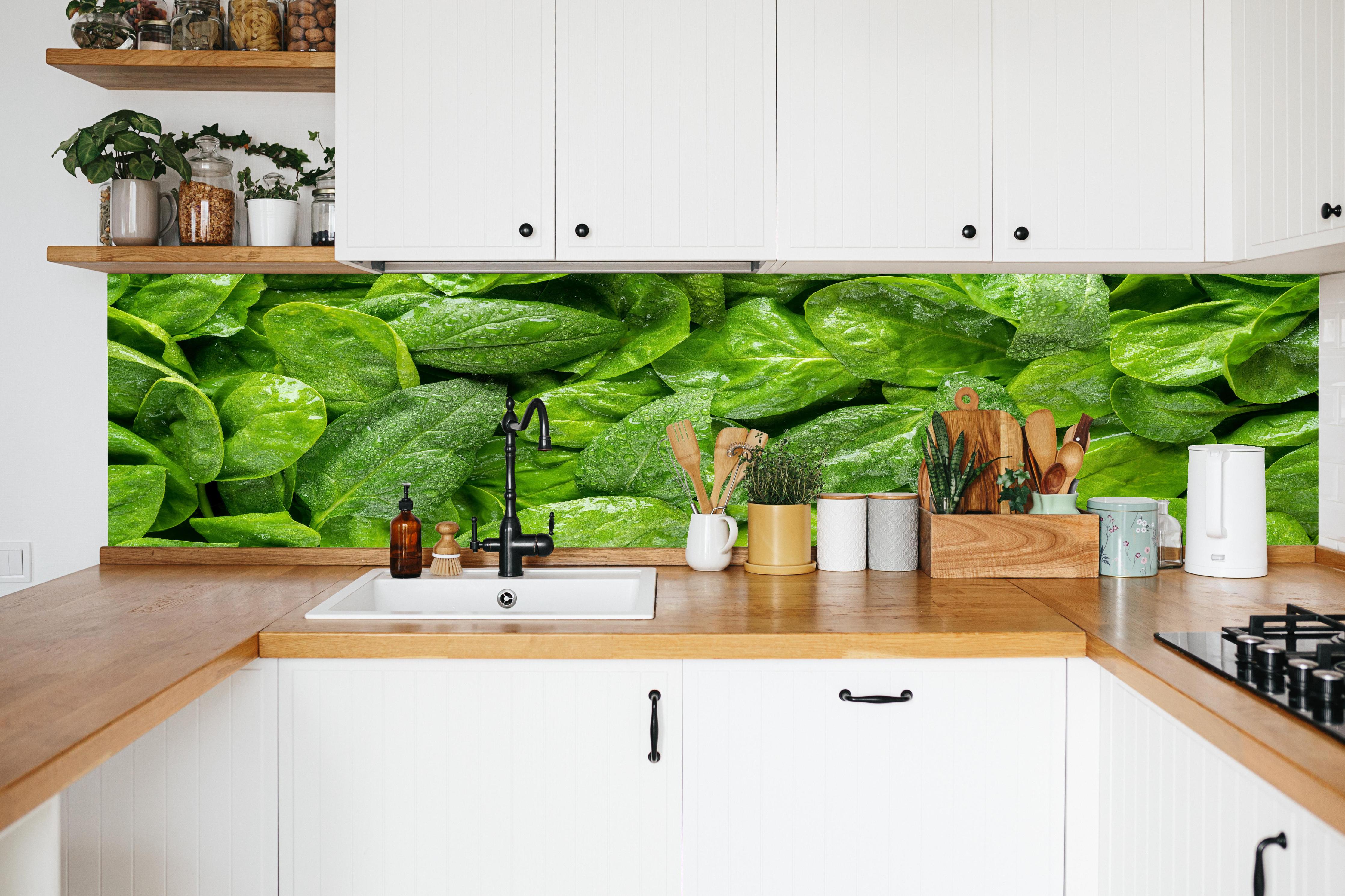 Küche - Grünes Kräuterblatt-Muster in weißer Küche hinter Gewürzen und Kochlöffeln aus Holz