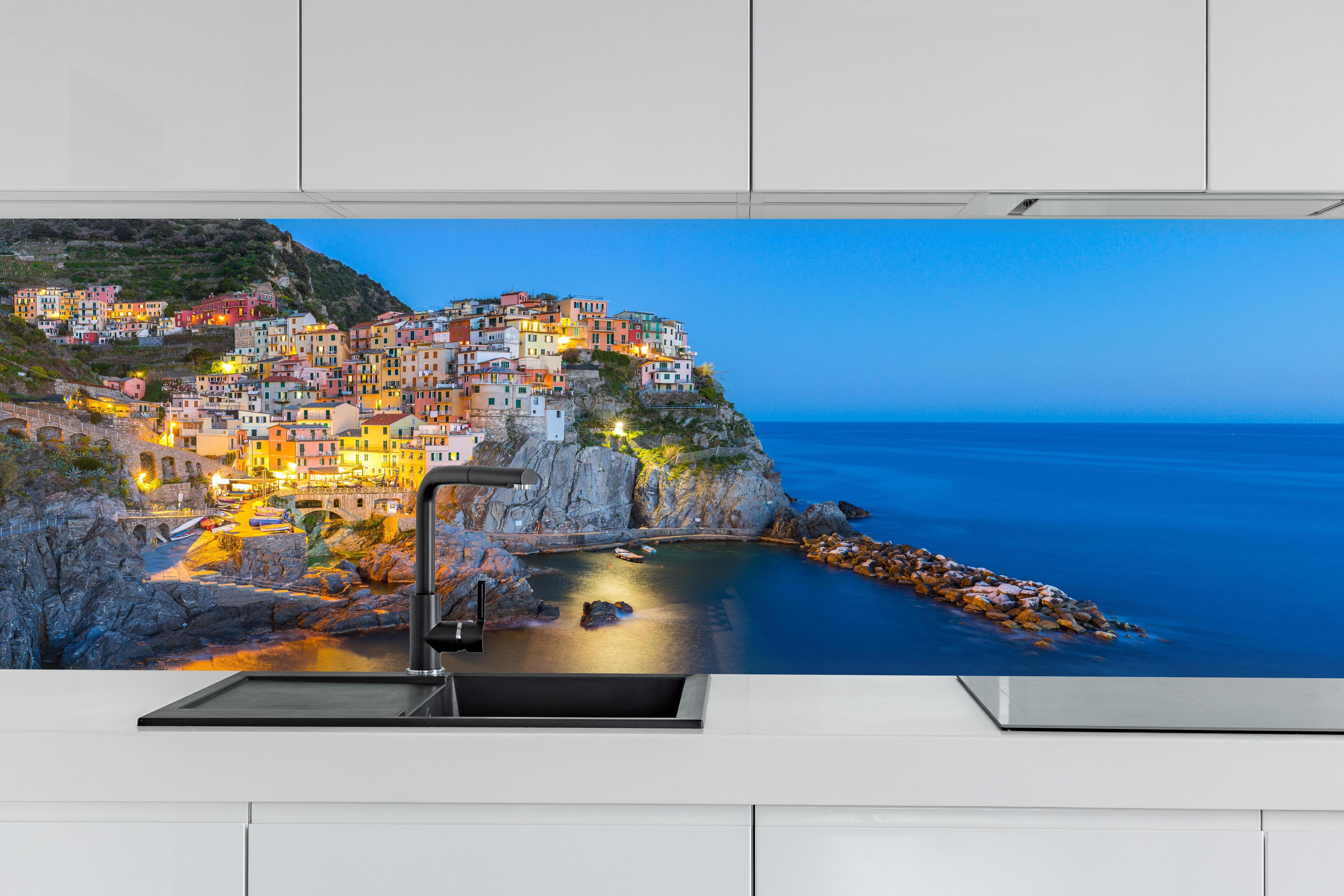 Küche - Italienische Küstenstadt bei Abendlicht hinter weißen Hochglanz-Küchenregalen und schwarzem Wasserhahn