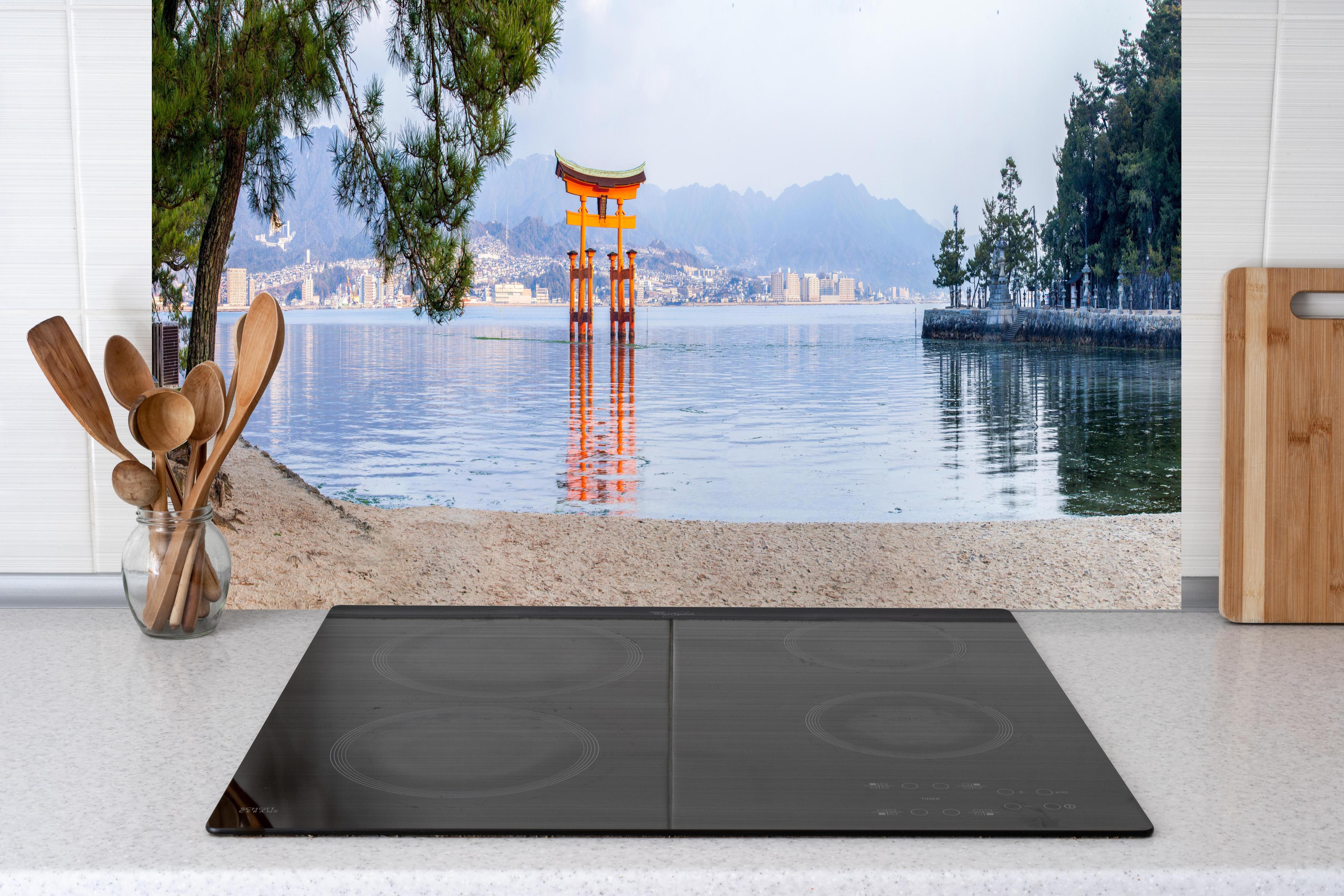 Küche - Japanisches Torii am Meer hinter Cerankochfeld und Holz-Kochutensilien