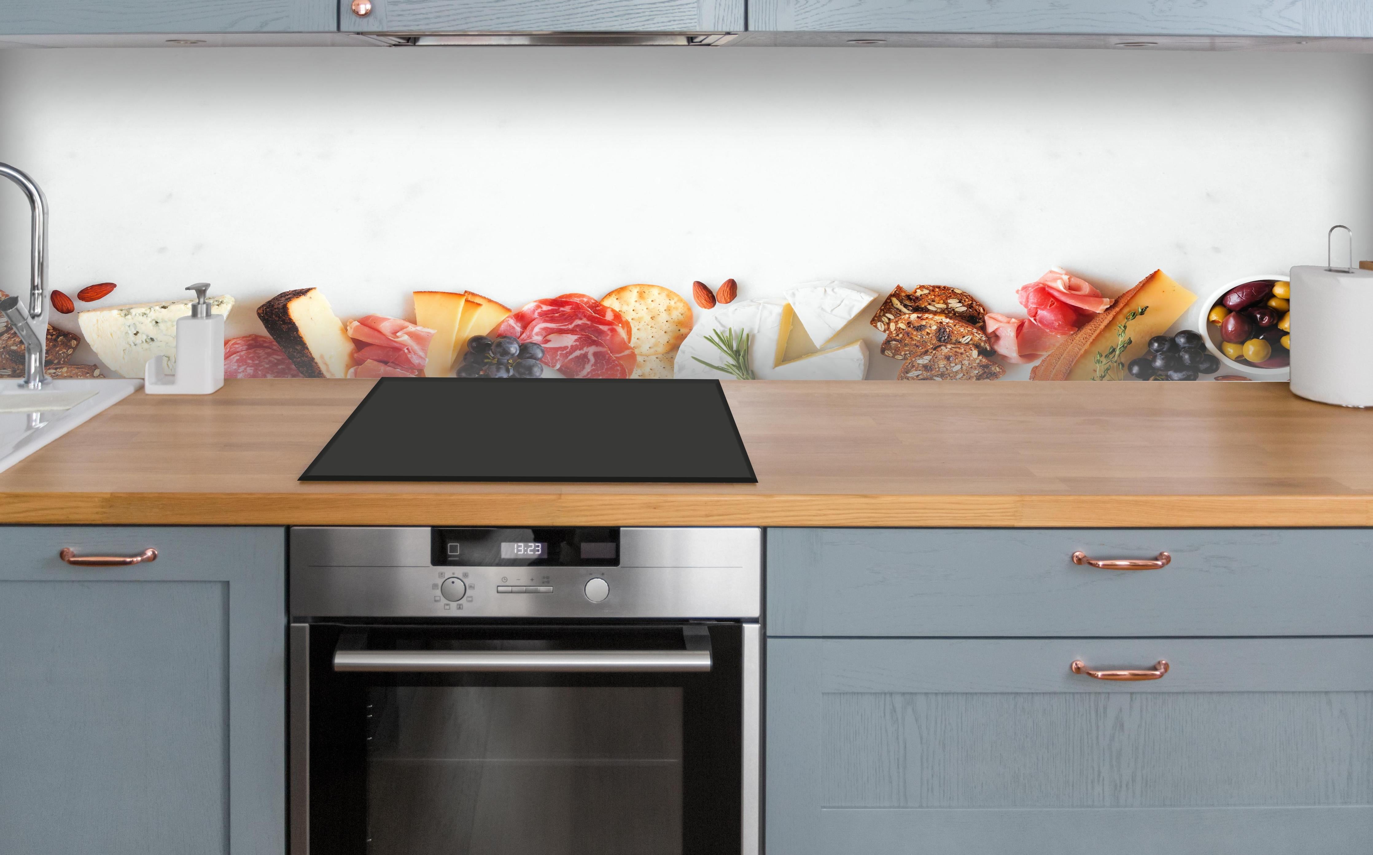 Küche - Käse und Antipasti auf Weiß über polierter Holzarbeitsplatte mit Cerankochfeld