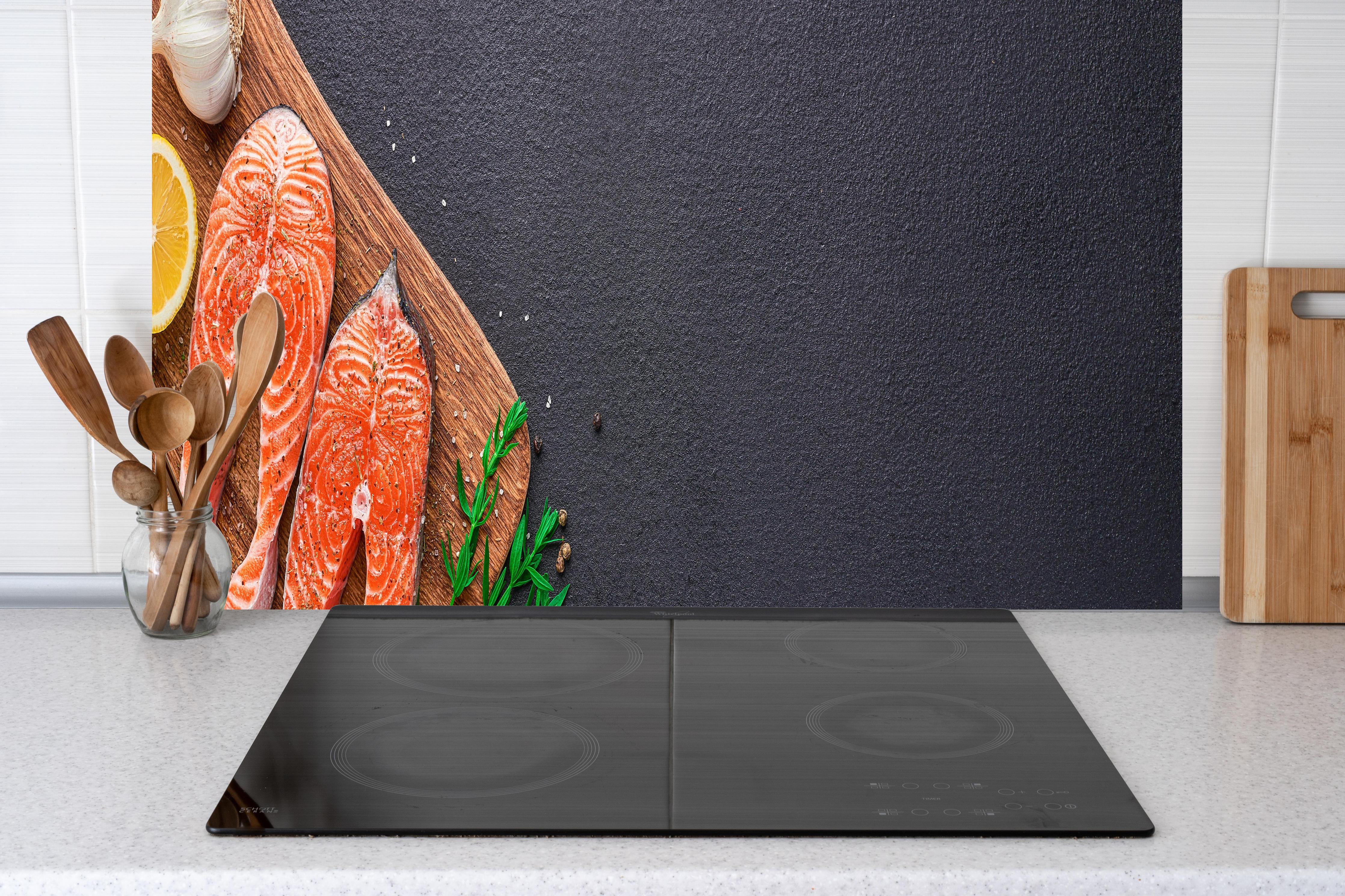 Küche - Lachssteaks auf Holzbrett hinter Cerankochfeld und Holz-Kochutensilien