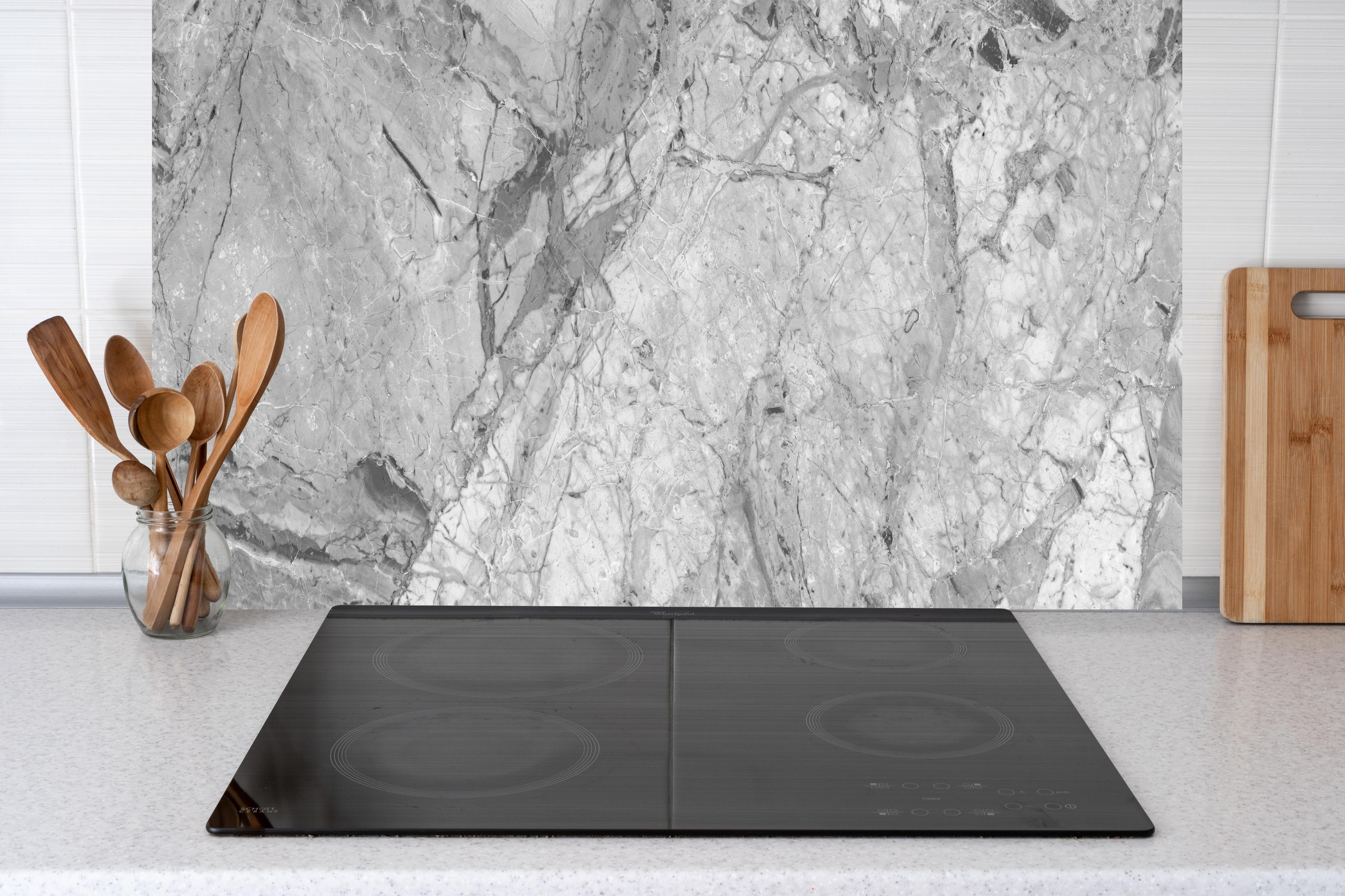 Küche - Luxuriöse Marmorstruktur in Weißgrau hinter Cerankochfeld und Holz-Kochutensilien