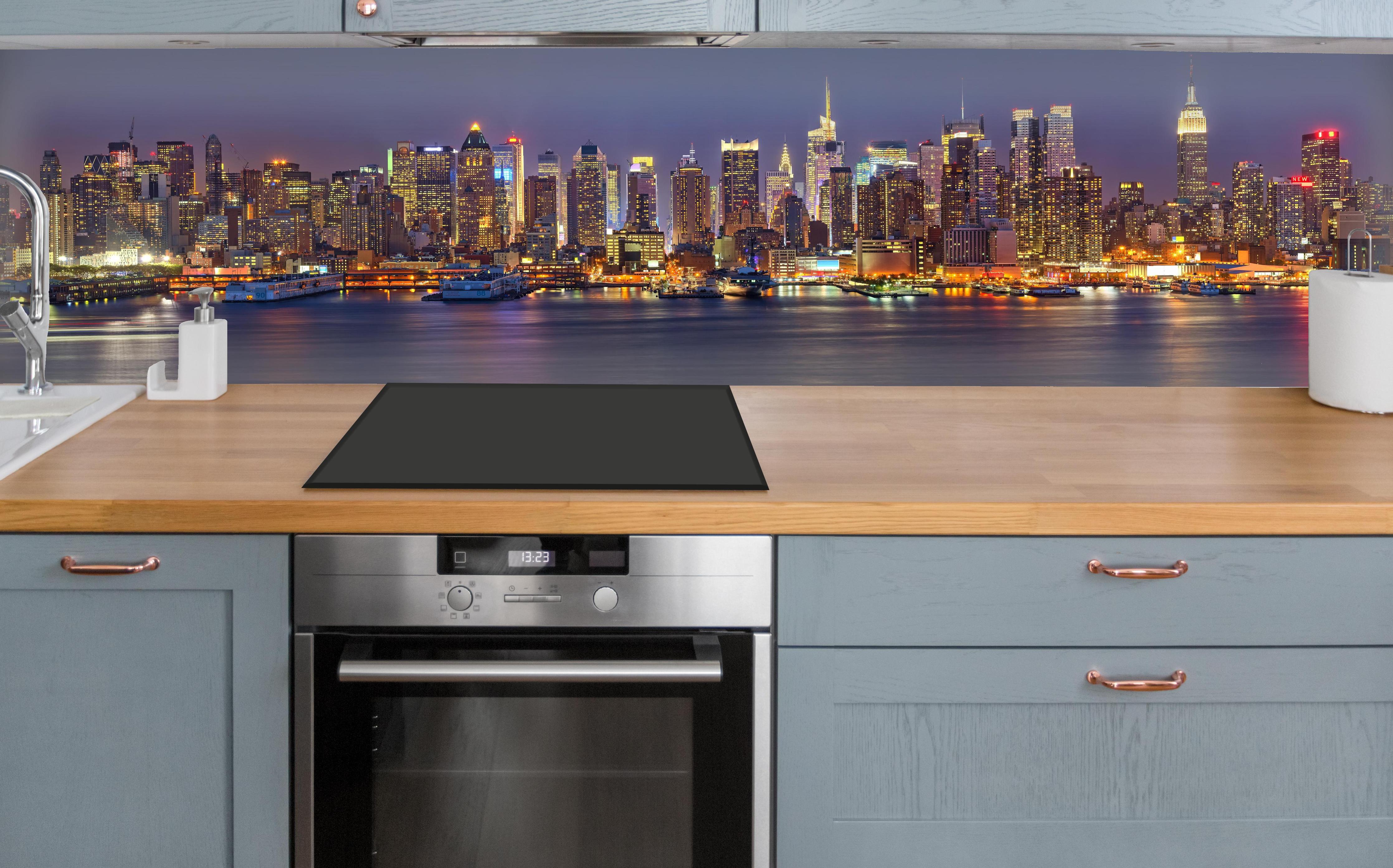 Küche - Manhattan Skyline bei Nacht über polierter Holzarbeitsplatte mit Cerankochfeld