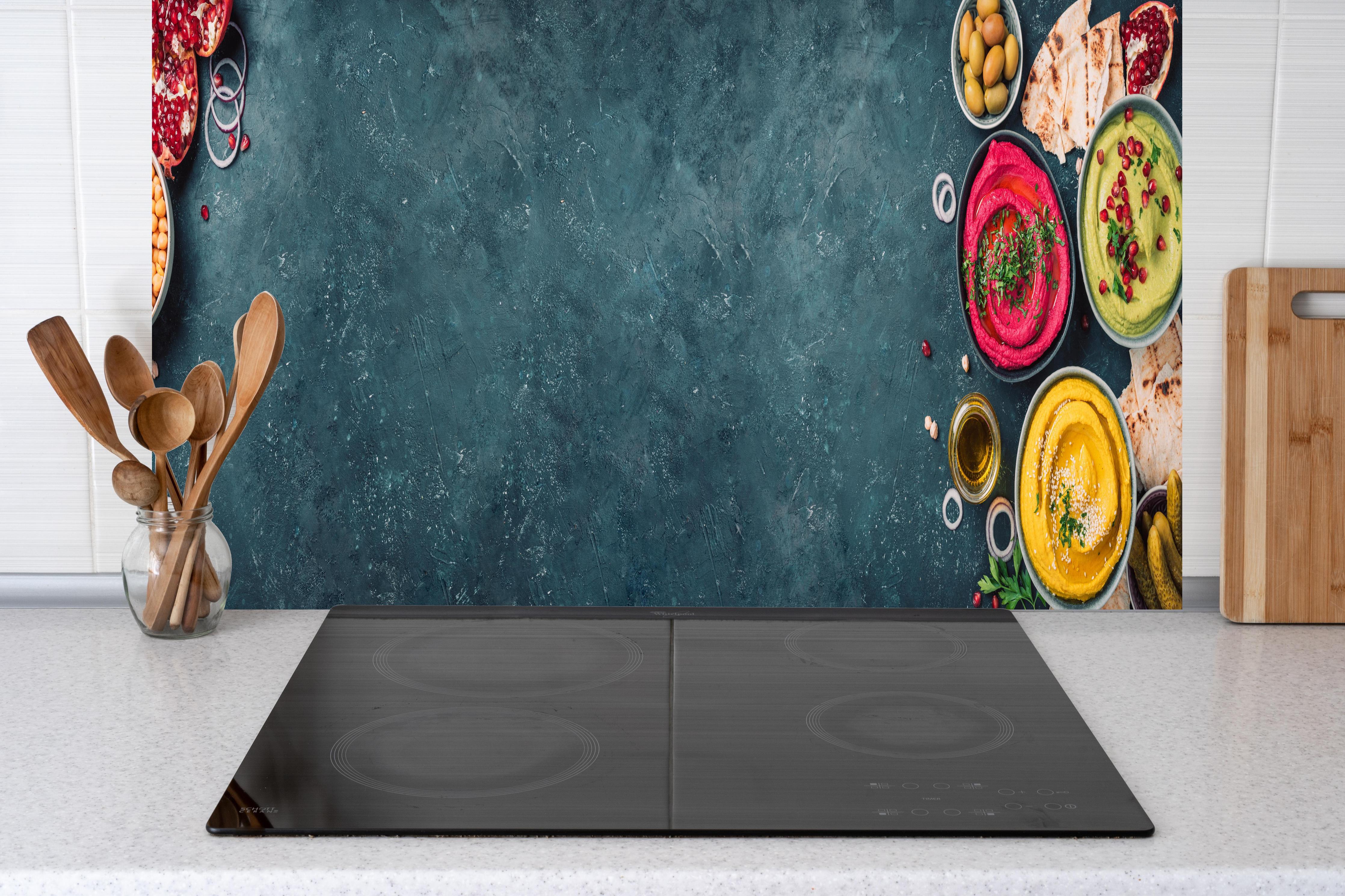 Küche - Mediterrane Gewürze und Oliven hinter Cerankochfeld und Holz-Kochutensilien