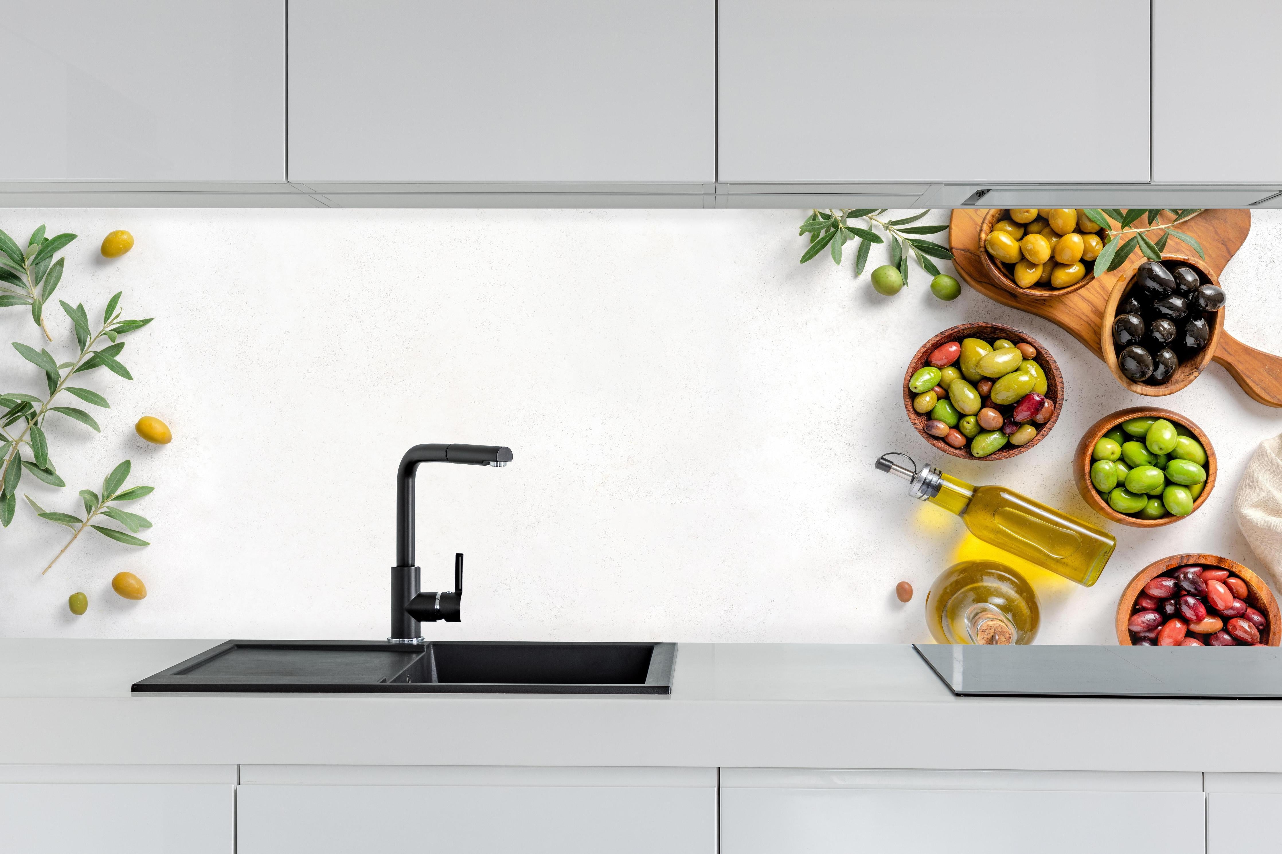 Küche - Mediterrane Oliven auf Weiß hinter weißen Hochglanz-Küchenregalen und schwarzem Wasserhahn
