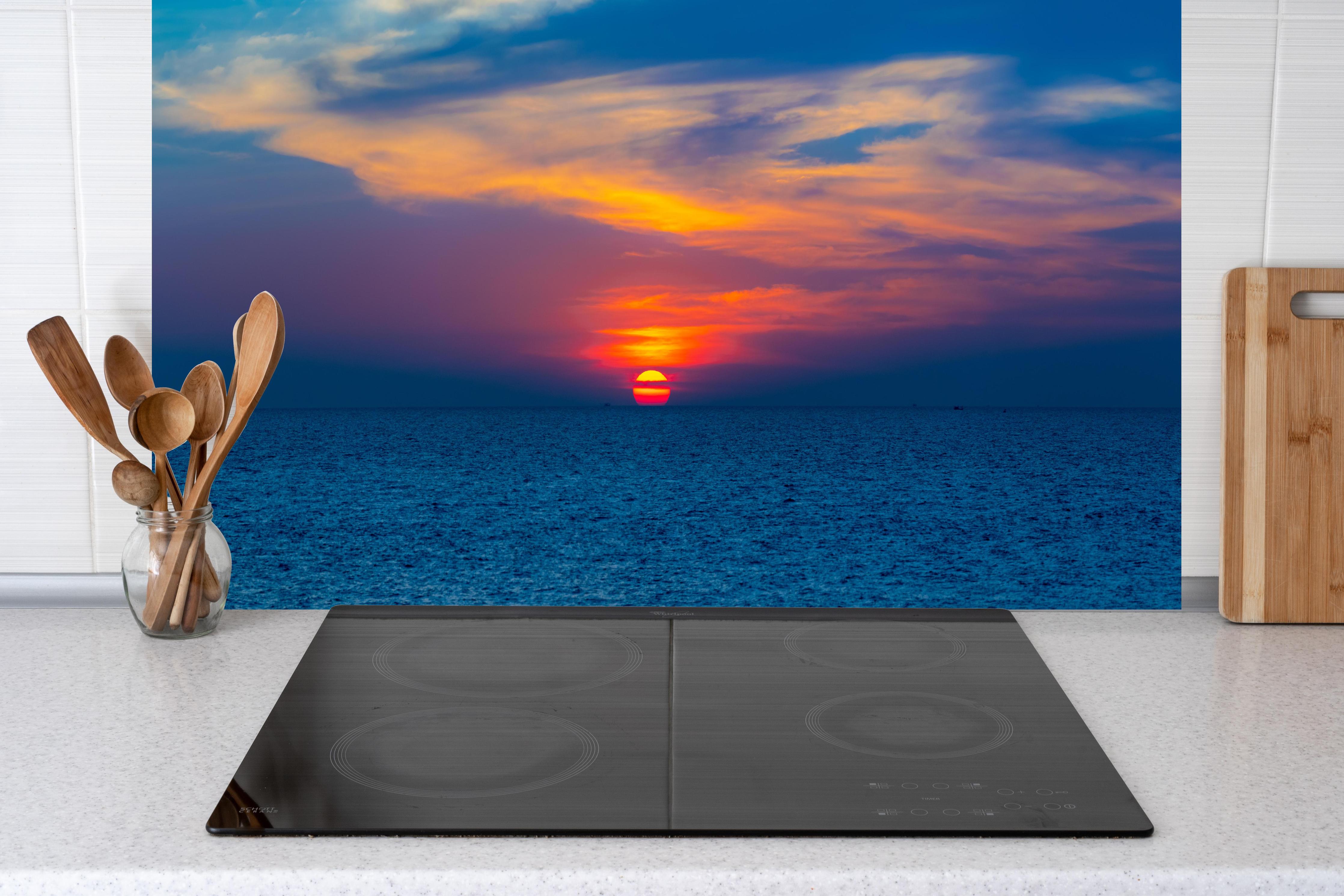 Küche - Meer-Sonnenuntergang Blau-Orange hinter Cerankochfeld und Holz-Kochutensilien